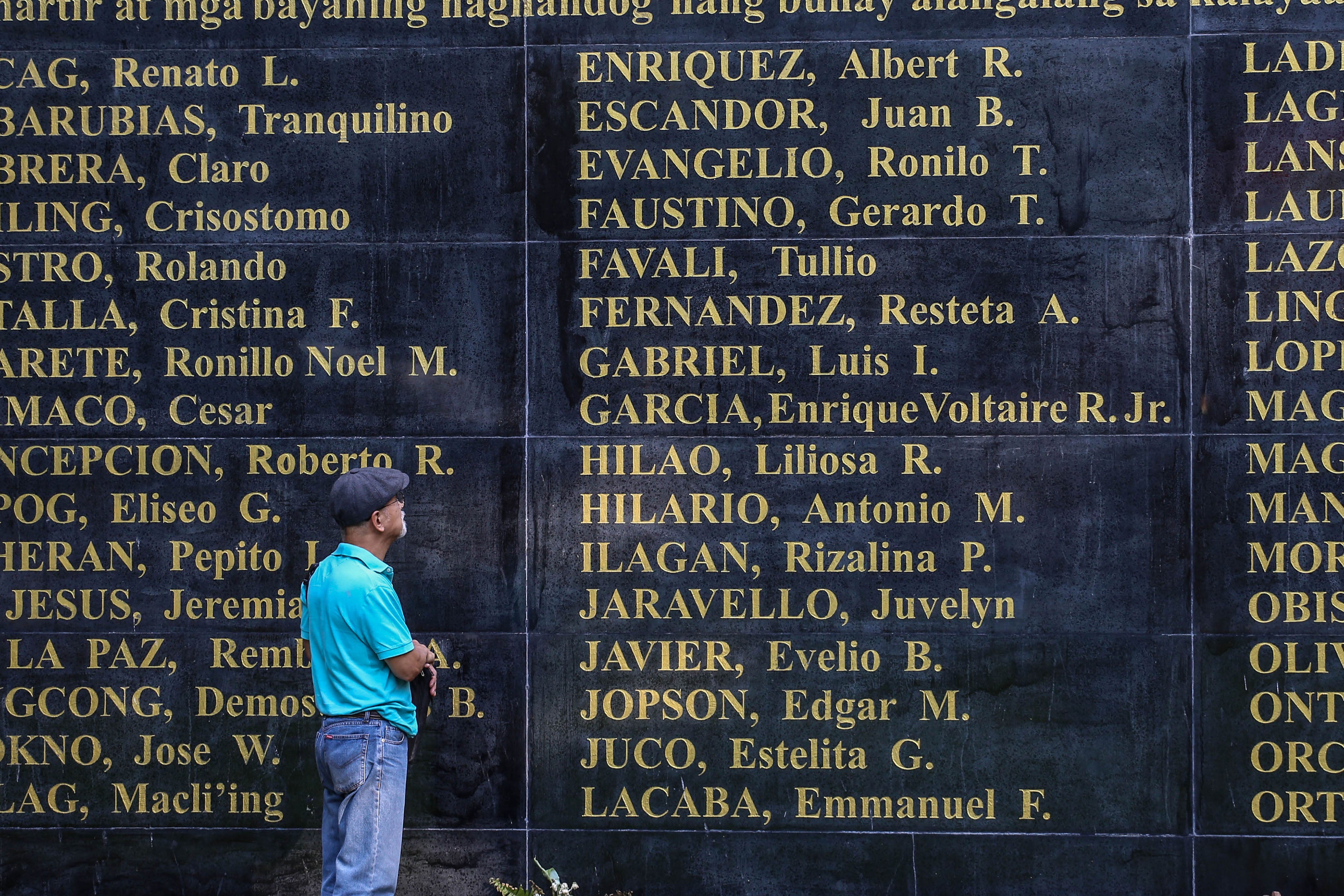 Ilagan looking at the Wall of Remembrance showing names of victims from the Martial Law era