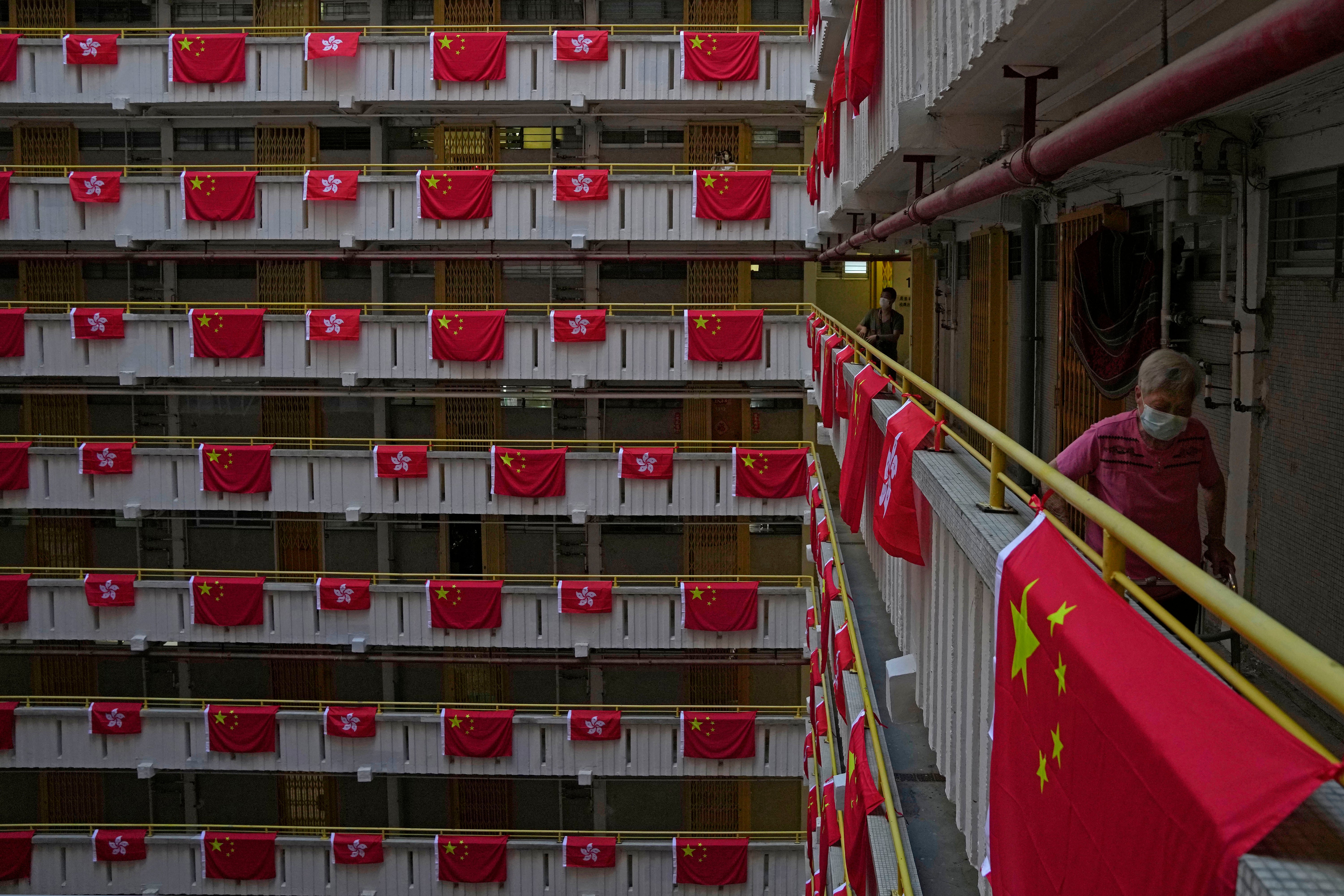 File photo: A resident walks besides Chinese and Hong Kong flags hanging from a residential building to celebrate the 25th anniversary of Hong Kong handover, at a public housing estate, in Hong Kong on 25 June