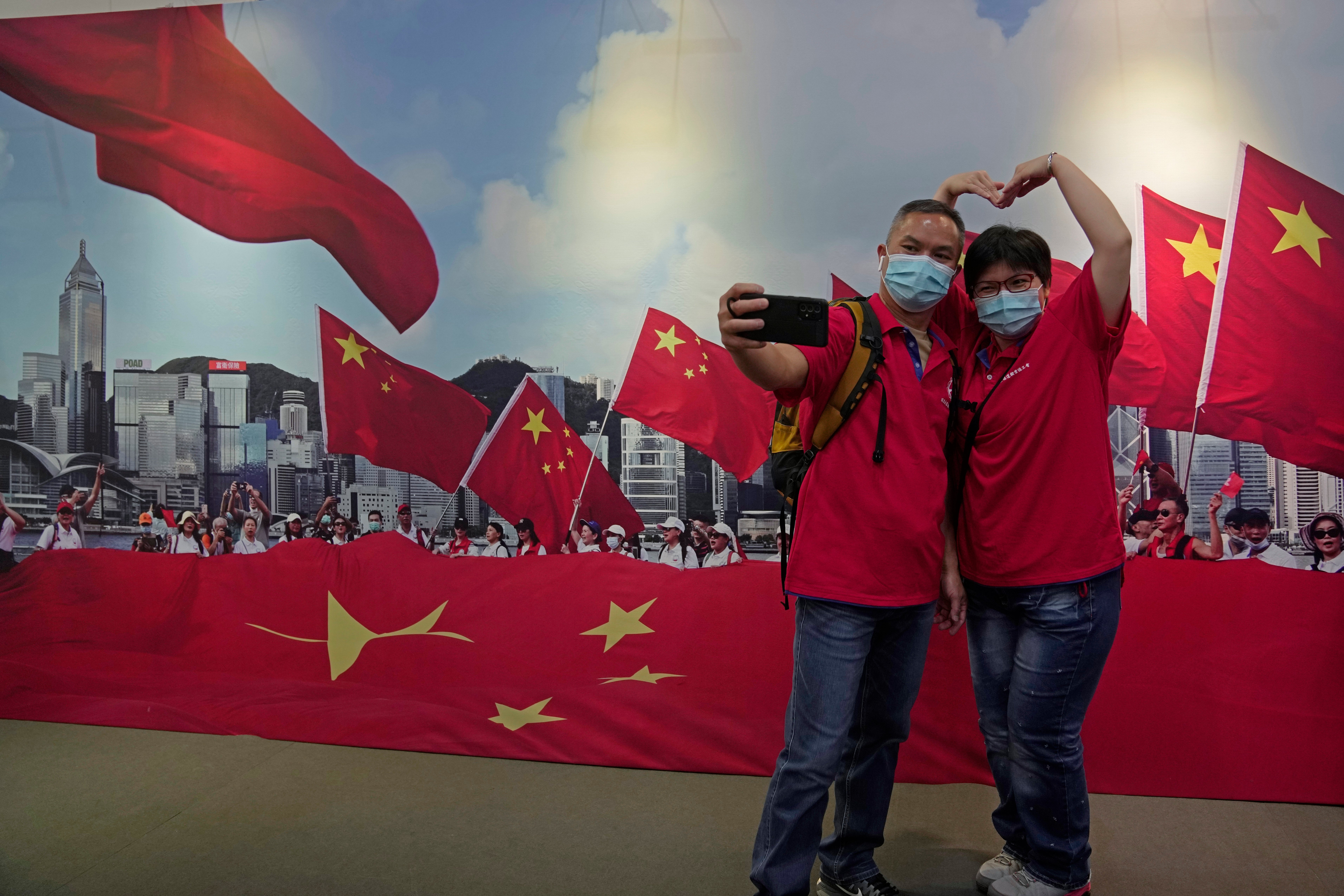 A couple pose in front of a banner featuring Chinese flags at an exhibition to mark the 25th anniversary of the former British colony’s return to Chinese rule, in Hong Kong on 24 June