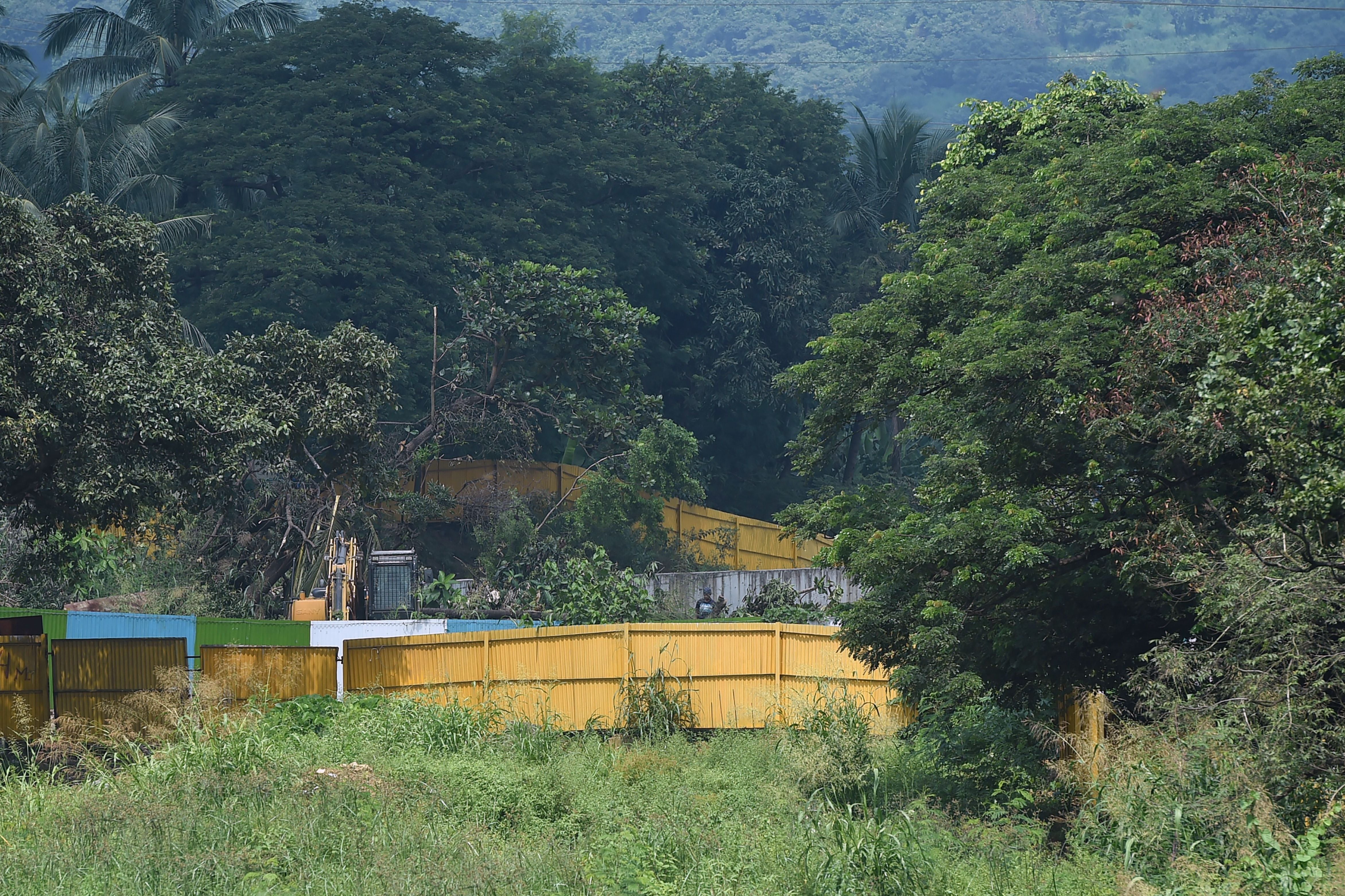 An excavator is pictured next to cut down trees at the construction site of a metro train car shed in the Aarey colony in Mumbai