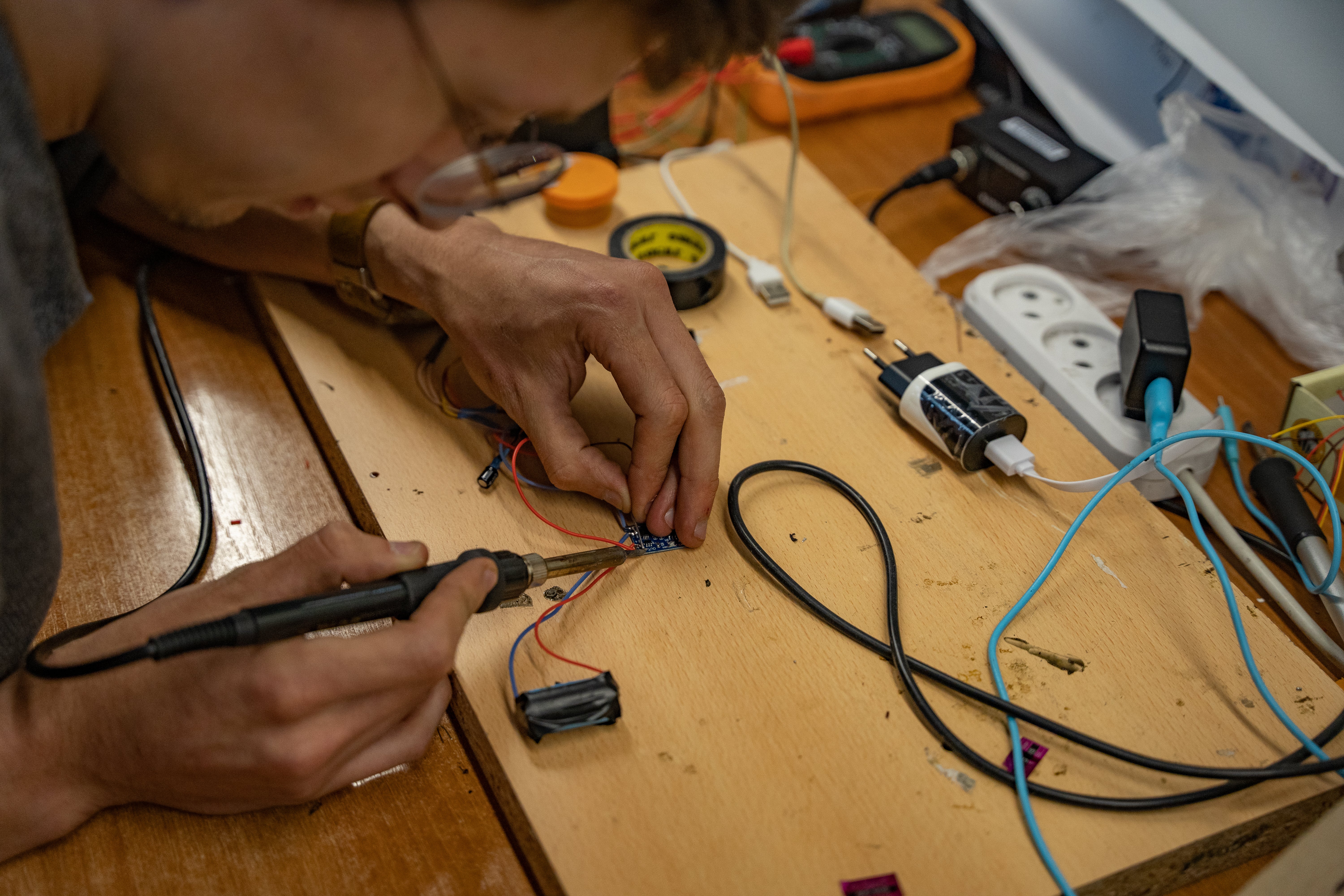 Maksym Sheremet solders a release device for a drone using a battery from an e-cigarette