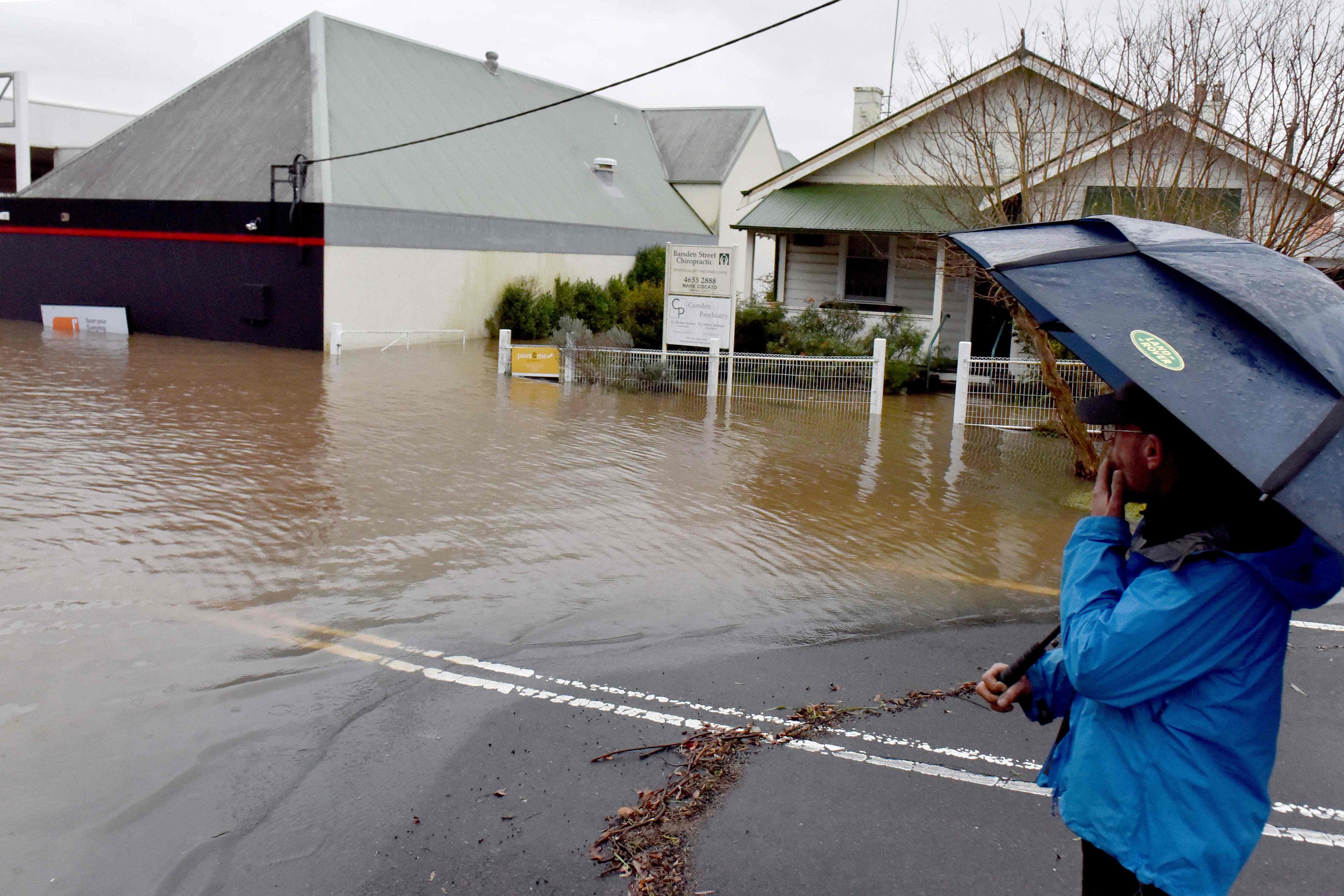 A man looks at a flooded residential area due to torrential rain in the Camden suburb of Sydney