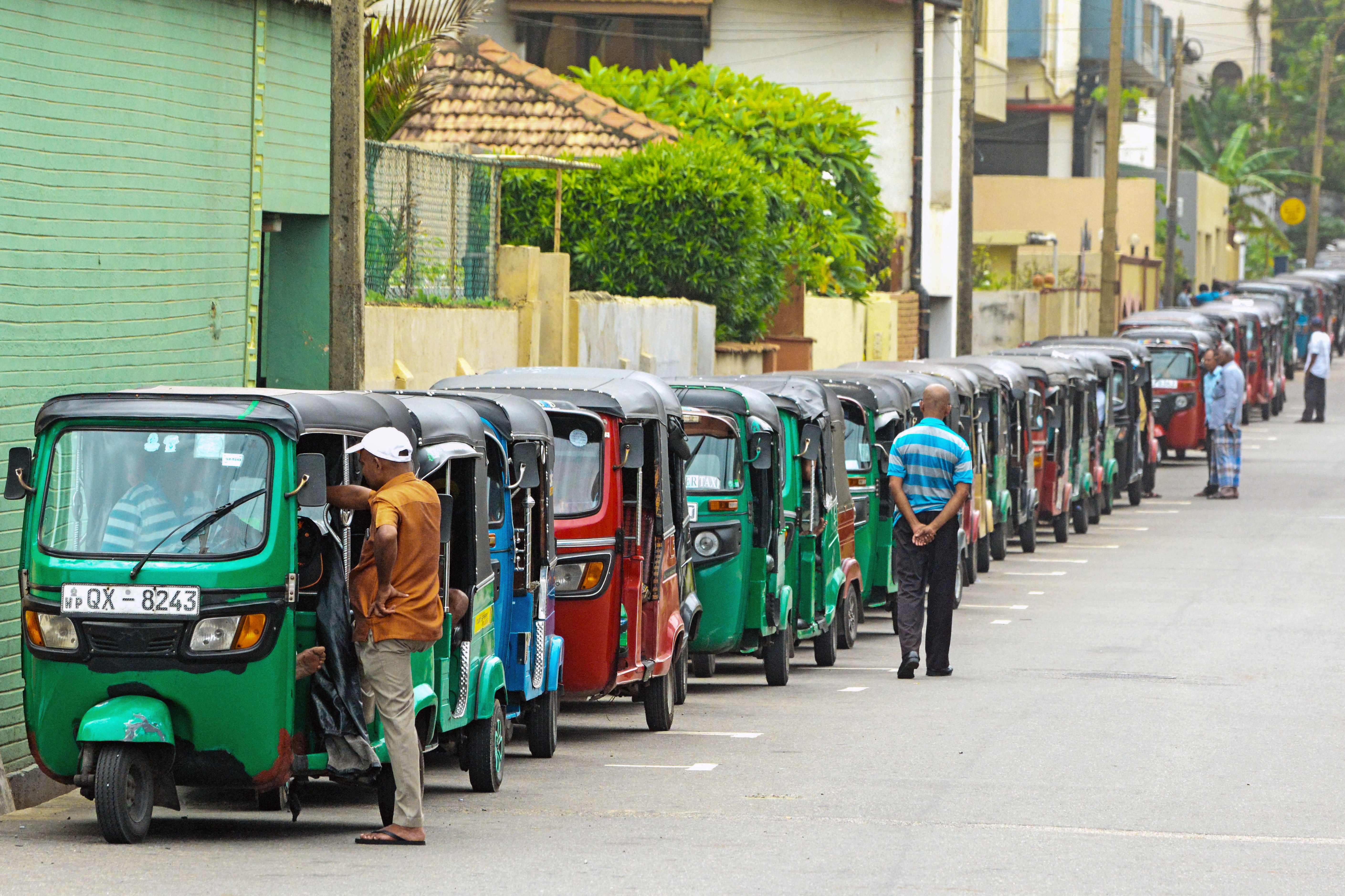 Auto rickshaw drivers queue along a street to buy fuel at a fuel station in Colombo