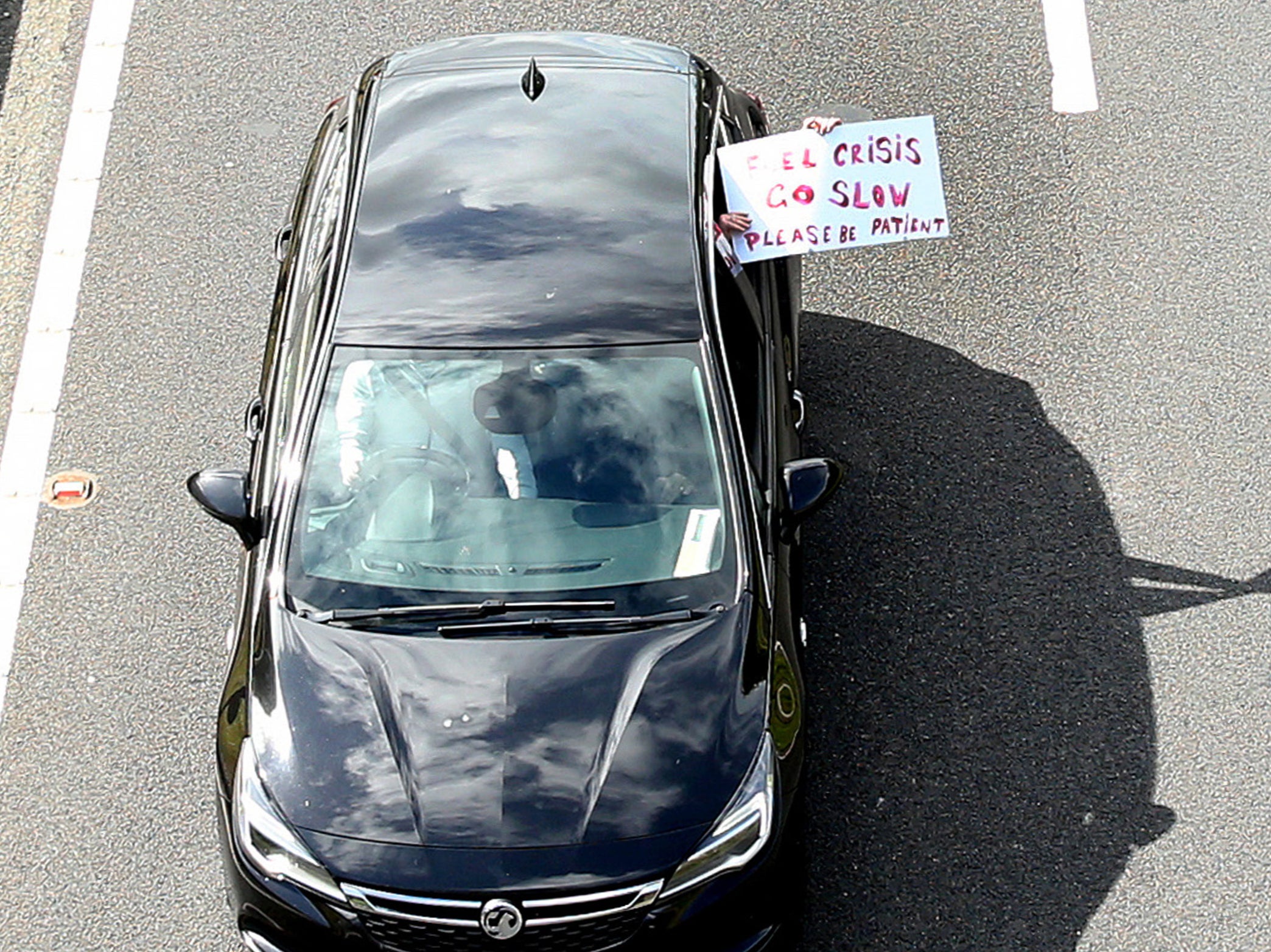 A protester holds a sign out of a car taking part in a slow-moving convoy along the A64