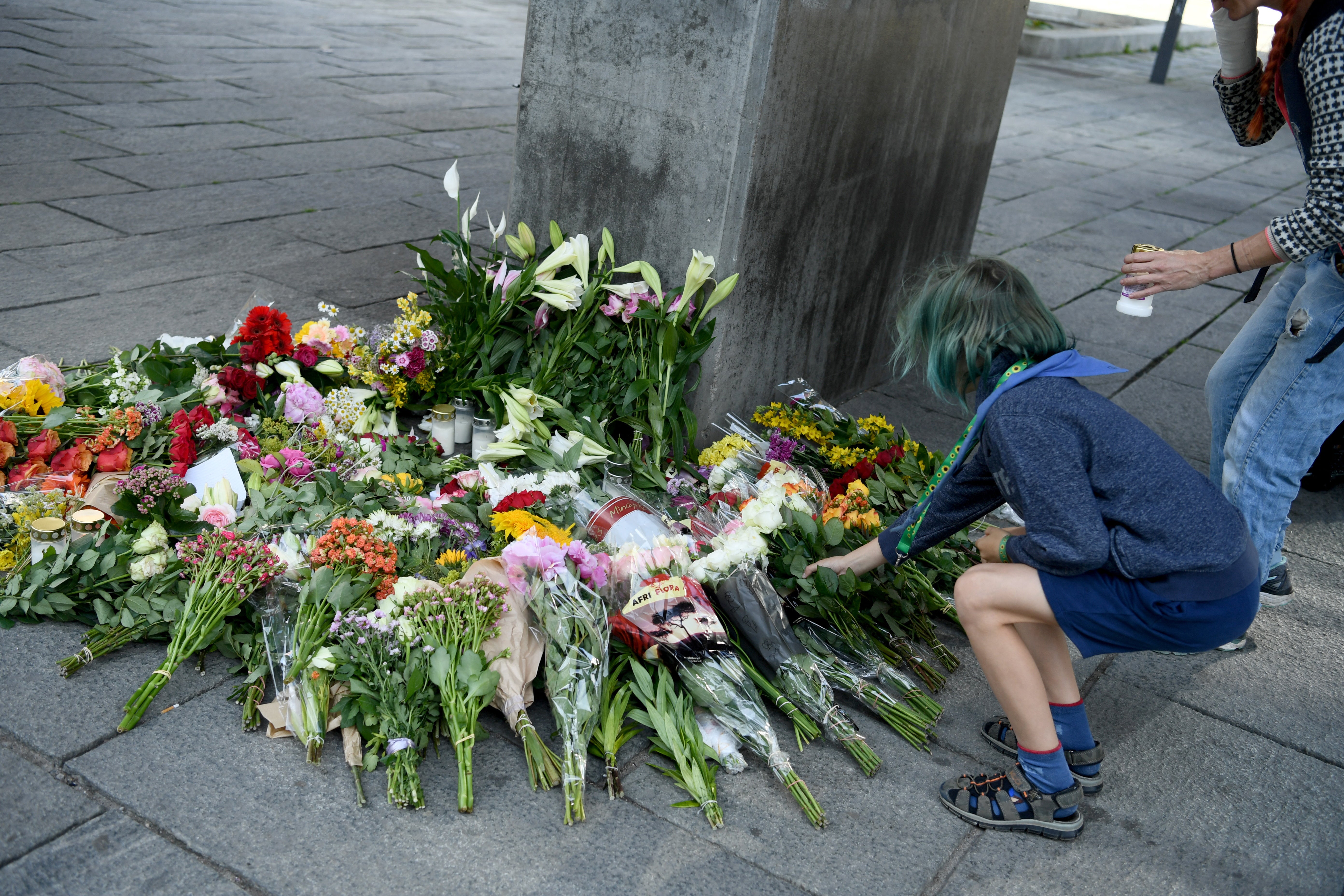 People place flowers and light candles next to the Field’s shopping centre