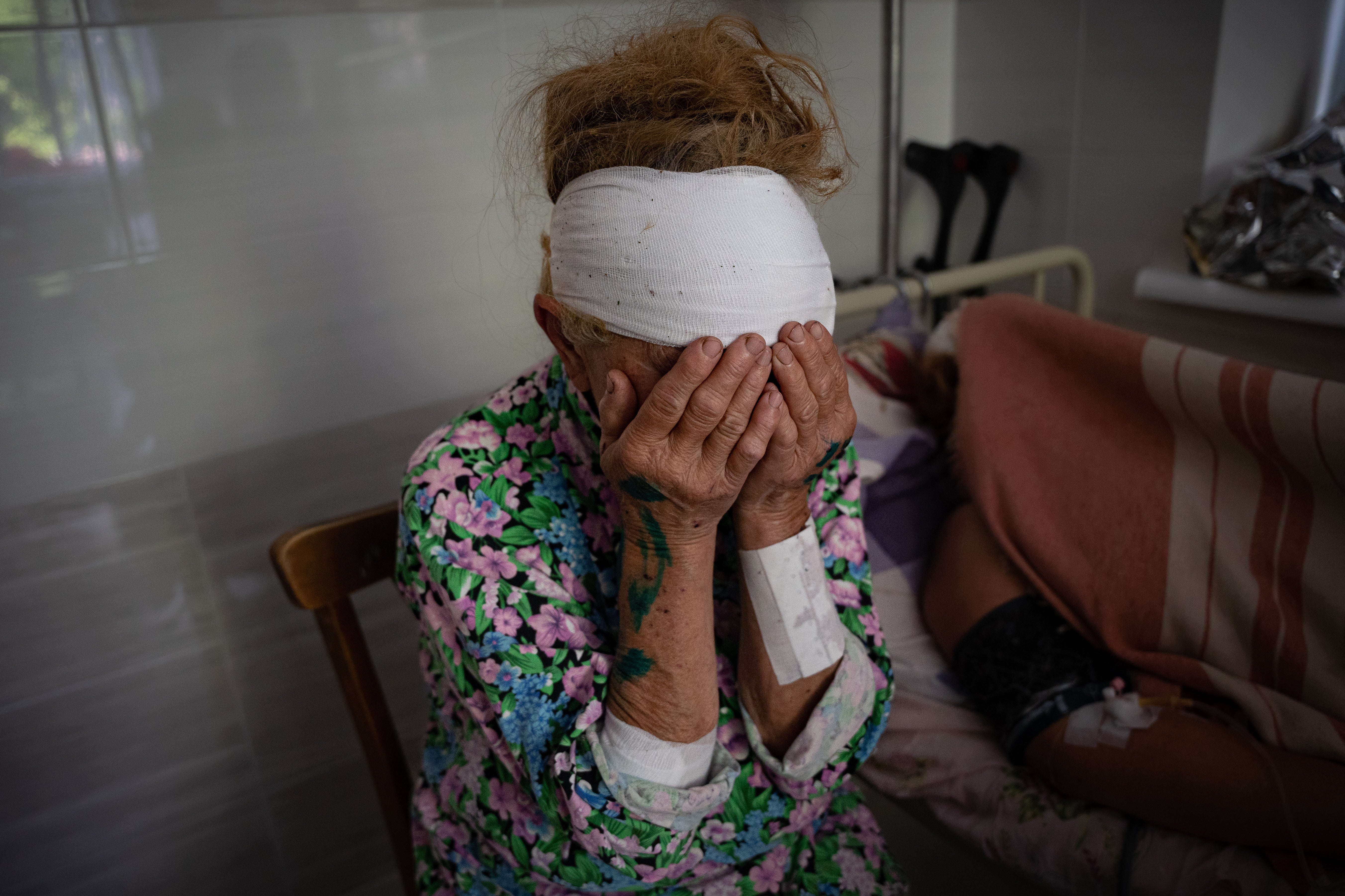 Olga, who was wounded by shelling on Monday, sits next to her neighbour who was badly injured and lost her daughter the day before in a missile strike