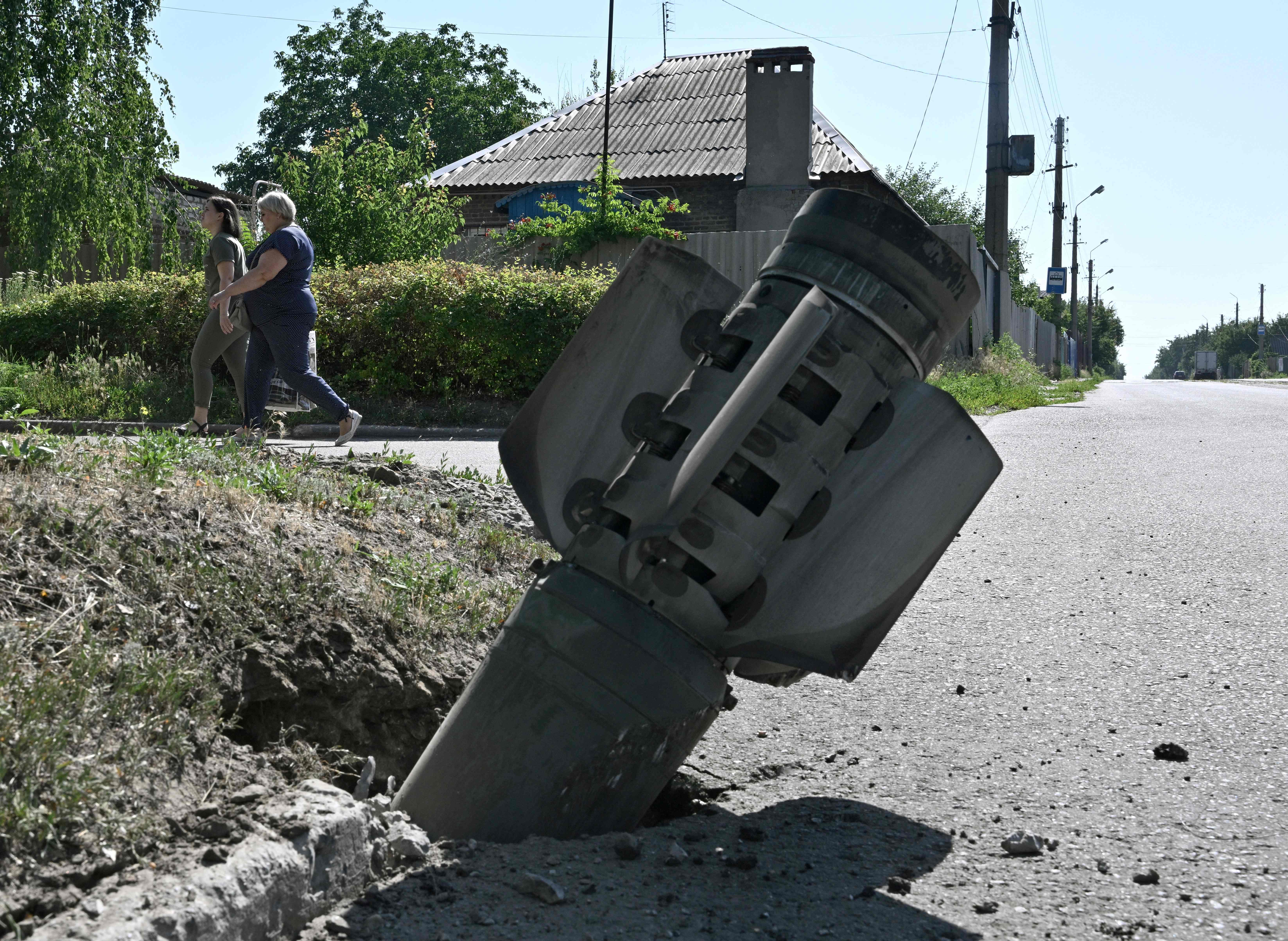 Pedestrians walk past the tail section of a rocket embedded in the ground in Kramatorsk on Monday, the day after a Russian rocket attack