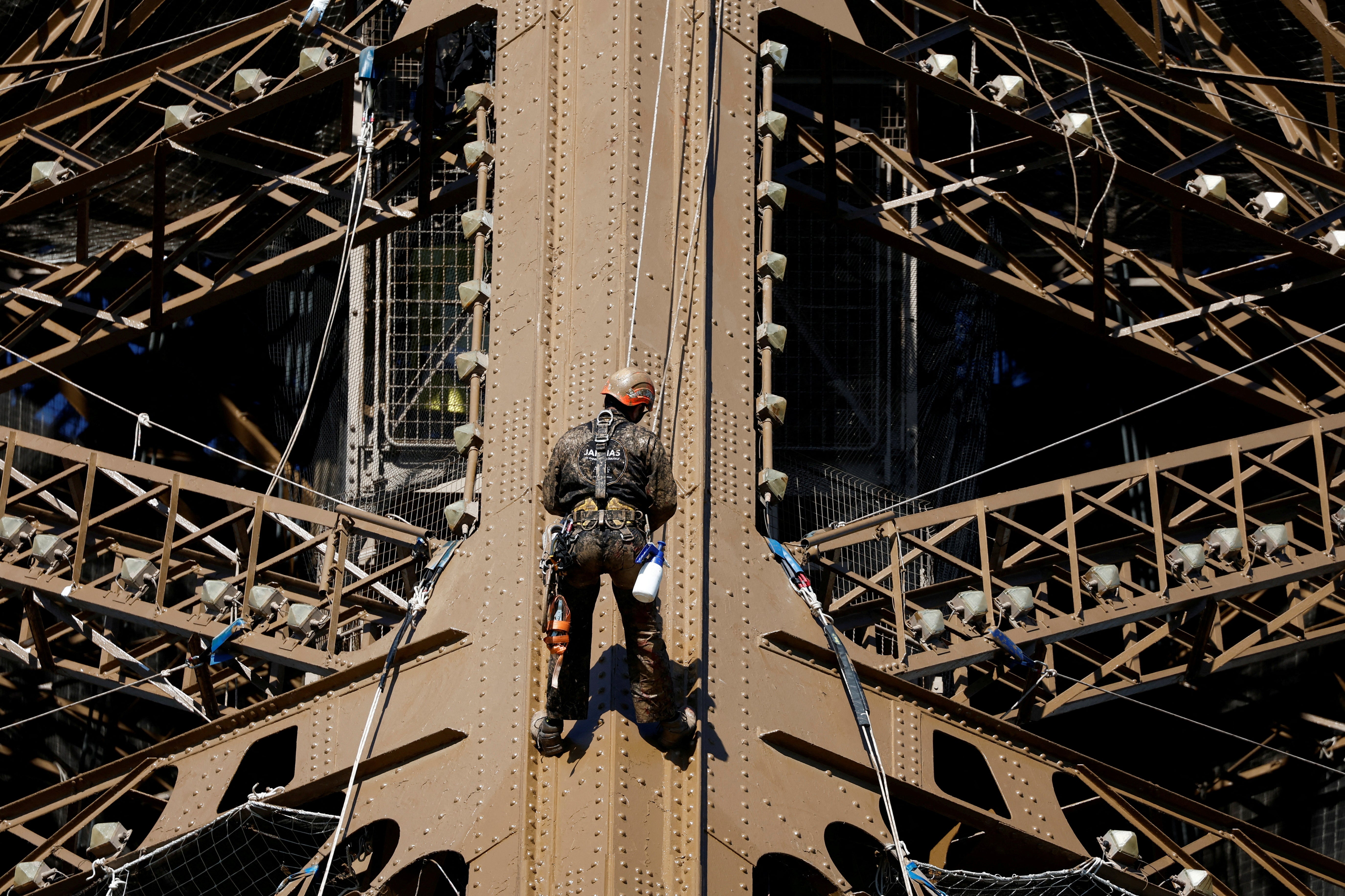 A worker is seen on the Eiffel tower during the 20th campaign of painting and stripping of the Eiffel tower in Paris, France