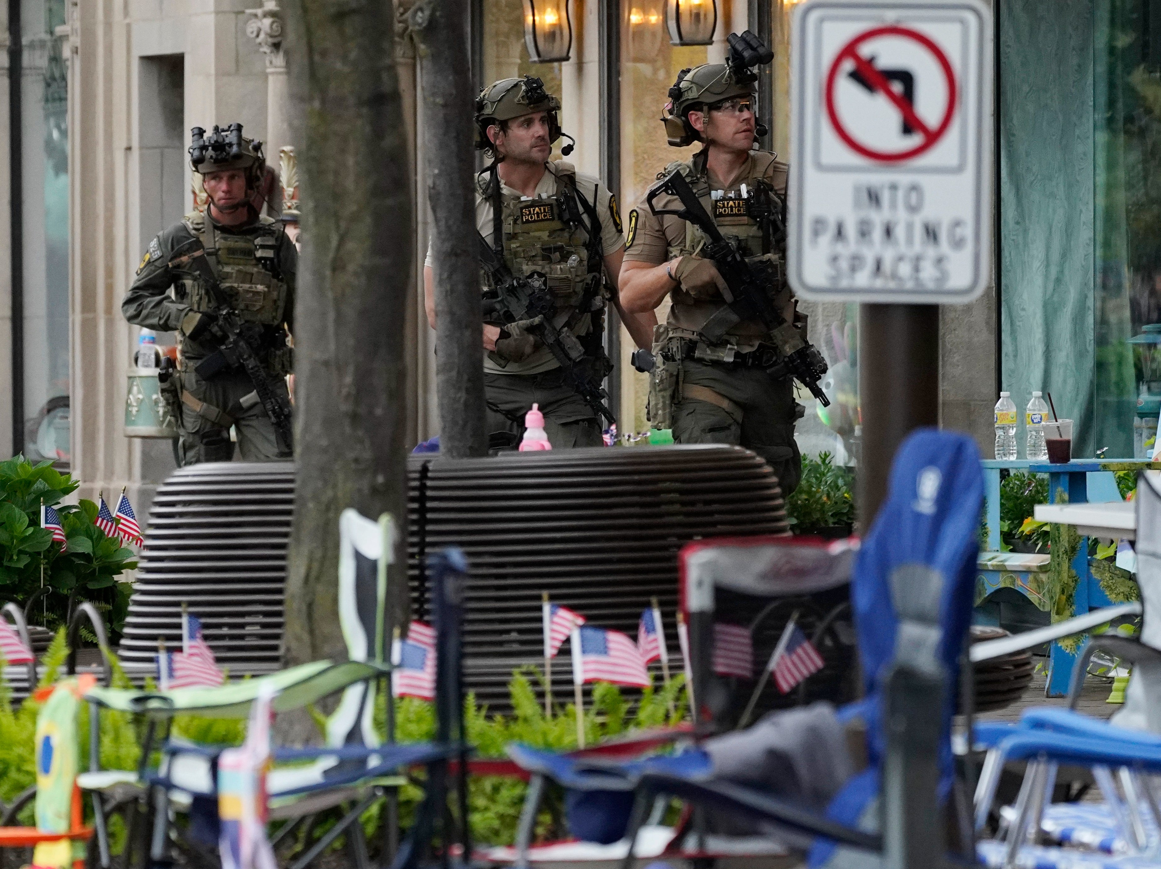 Armed police officers search the area after the mass shooting at the Highland Park Fourth of July parade