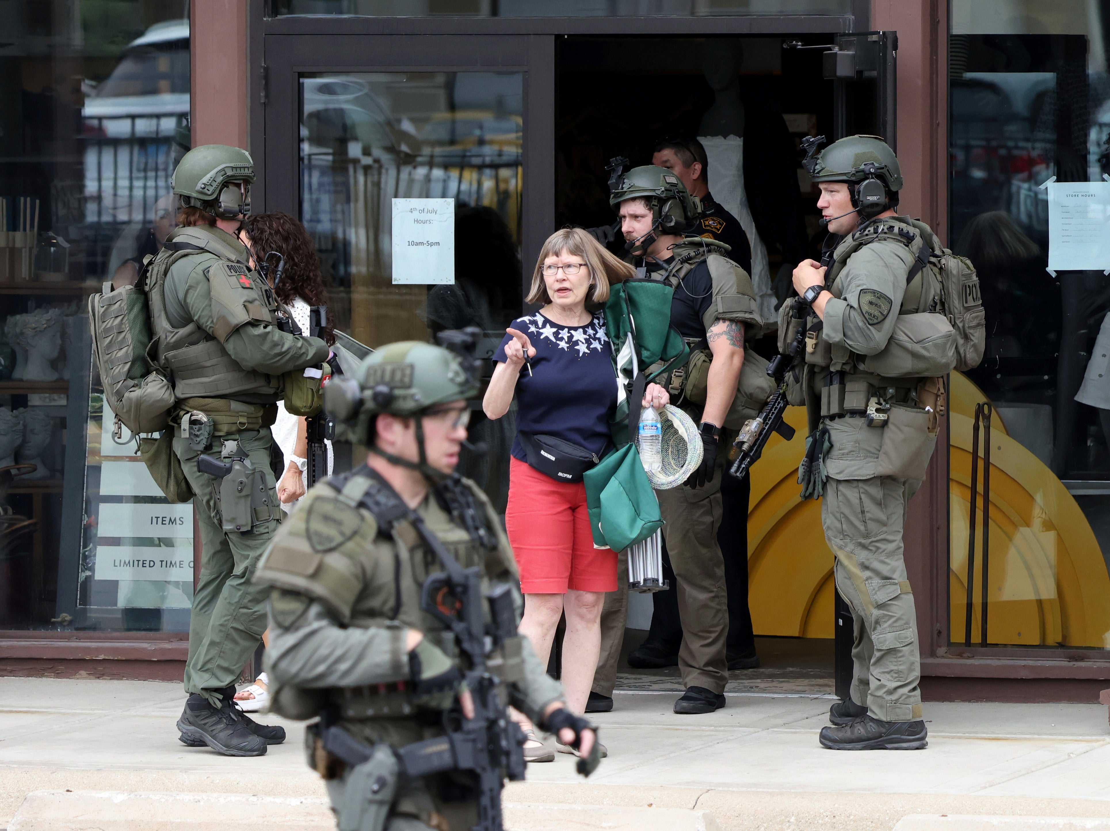 Law enforcement officers help evacuate people from a store in Highland Park