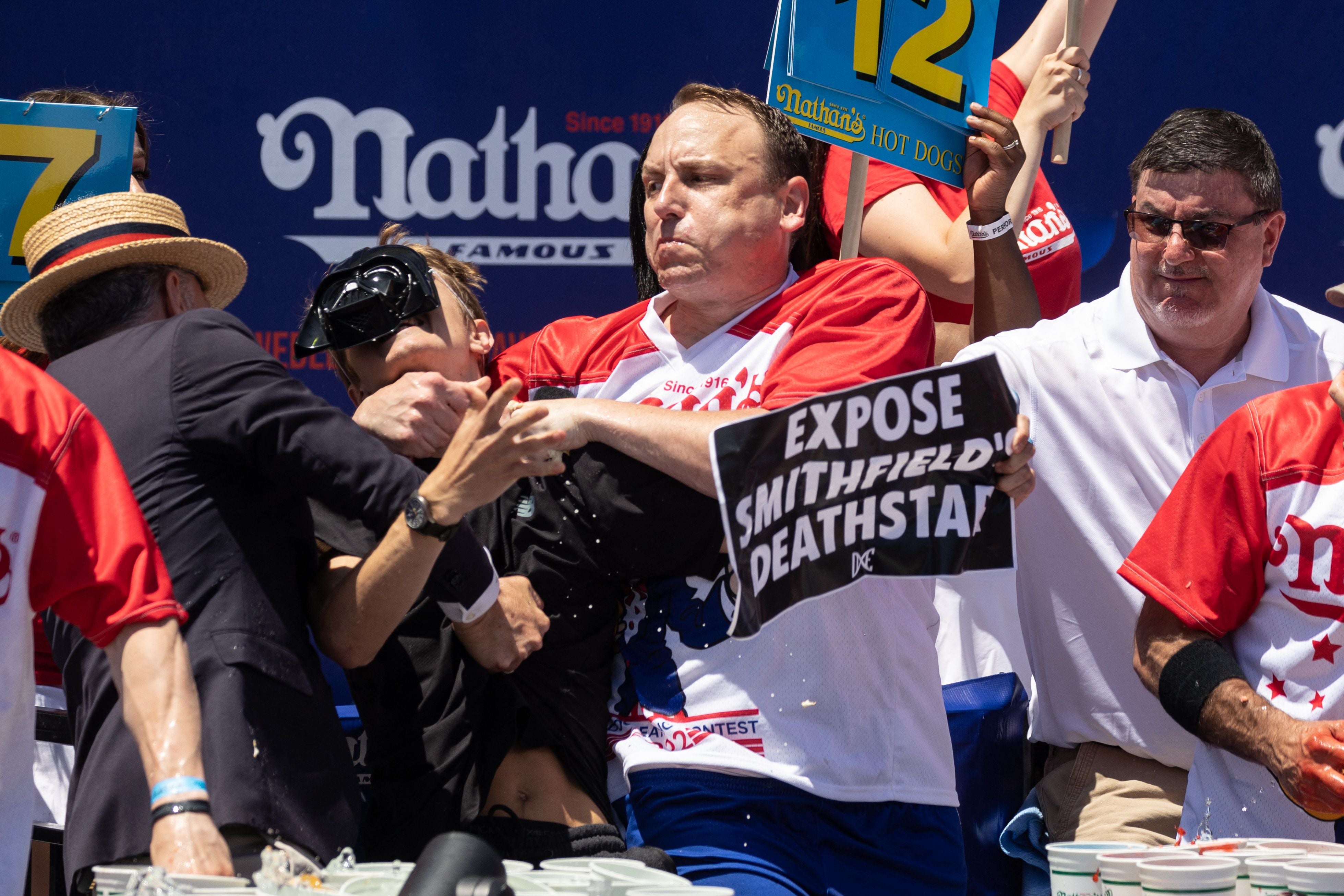 Joey Chestnut tackles a protester who interrupted the competition during the 2022 Nathan's Famous Fourth of July hot dog eating contest on Coney Island on July 4, 2022 in New York