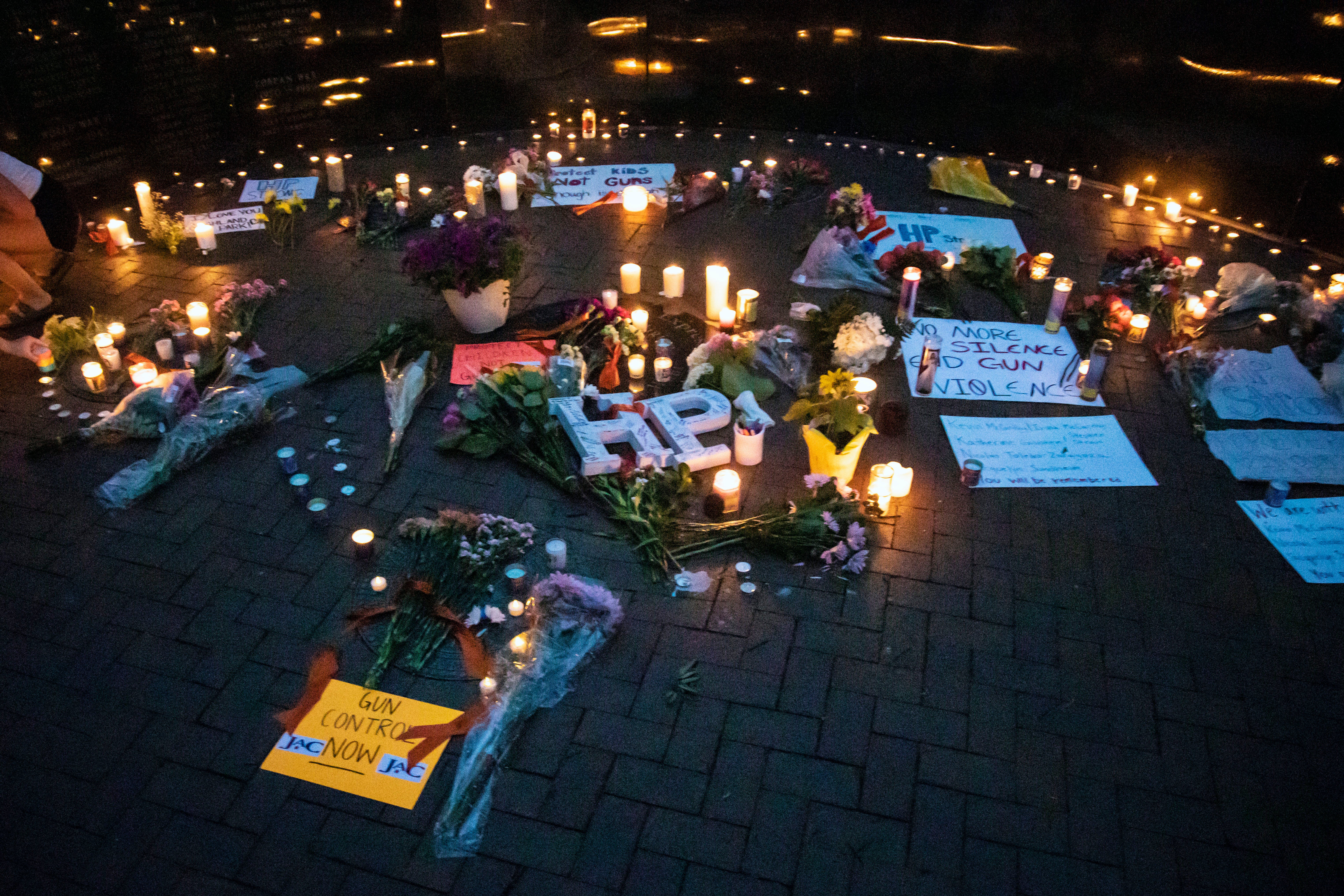 Dozens of mourners gather for a vigil near Central Avenue and St Johns Avenue in downtown Highland Park, one day after a gunman killed at least seven people and wounded dozens more by firing an AR-15-style rifle from a rooftop onto a crowd attending Highland Park's Fourth of July parade