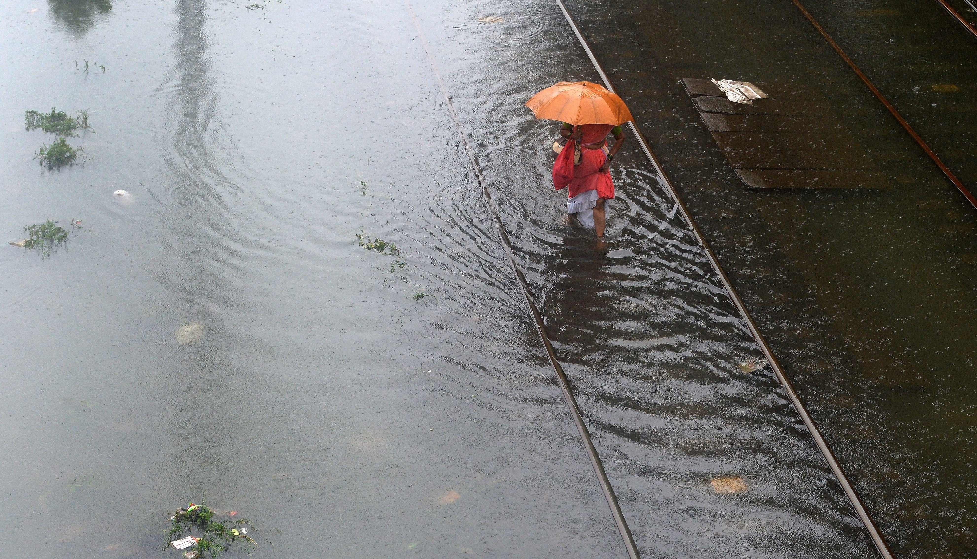 An Indian woman wades through waterlogged railway tracks in Mumbai