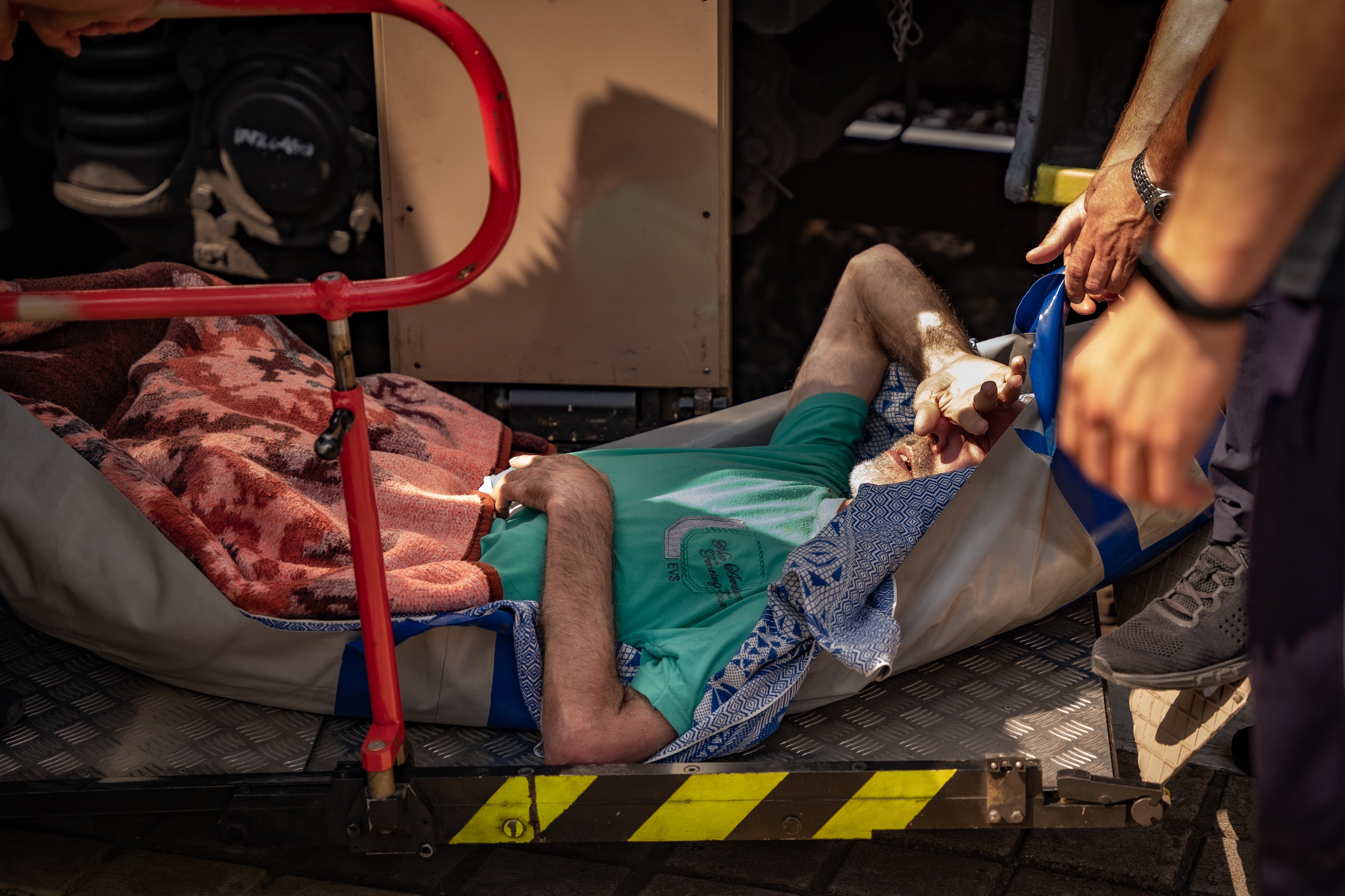 An elderly injured man is carried by medics onto an evacuation train in Donbas