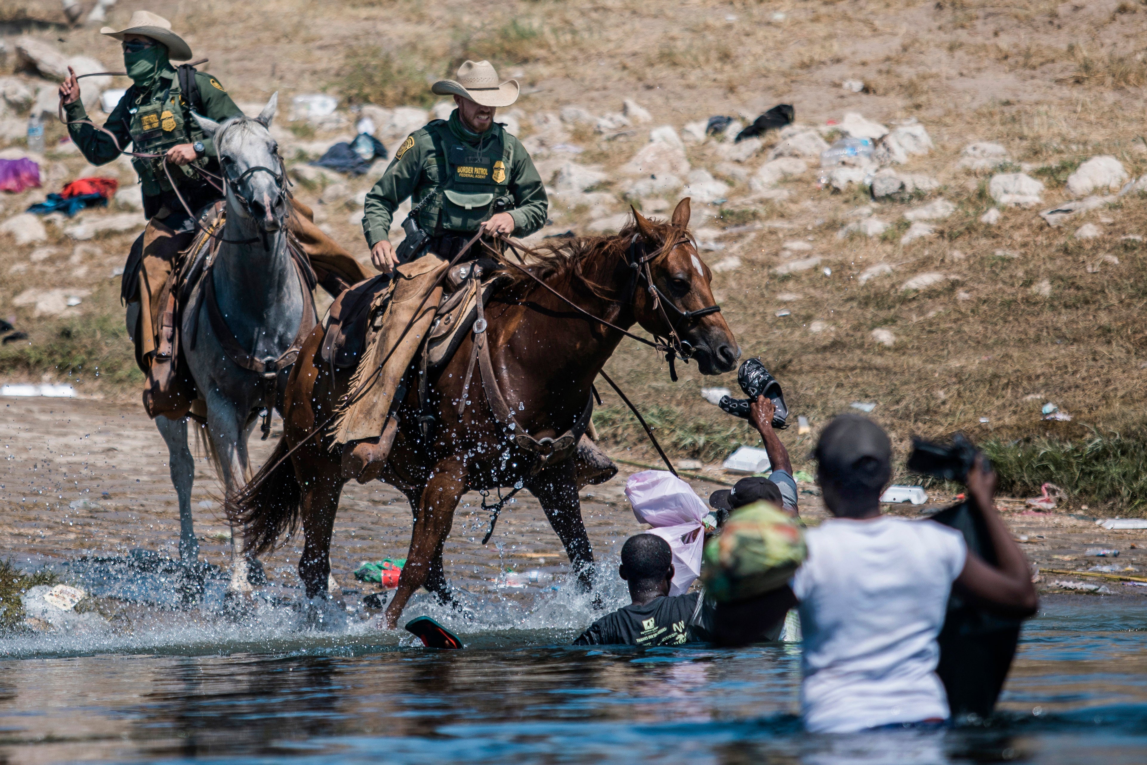 Mounted U.S. Border Patrol agents attempt to contain migrants as they cross the Rio Grande from Ciudad AcuÃ±a, Mexico, into Del Rio, Texas, Sept. 19, 2021