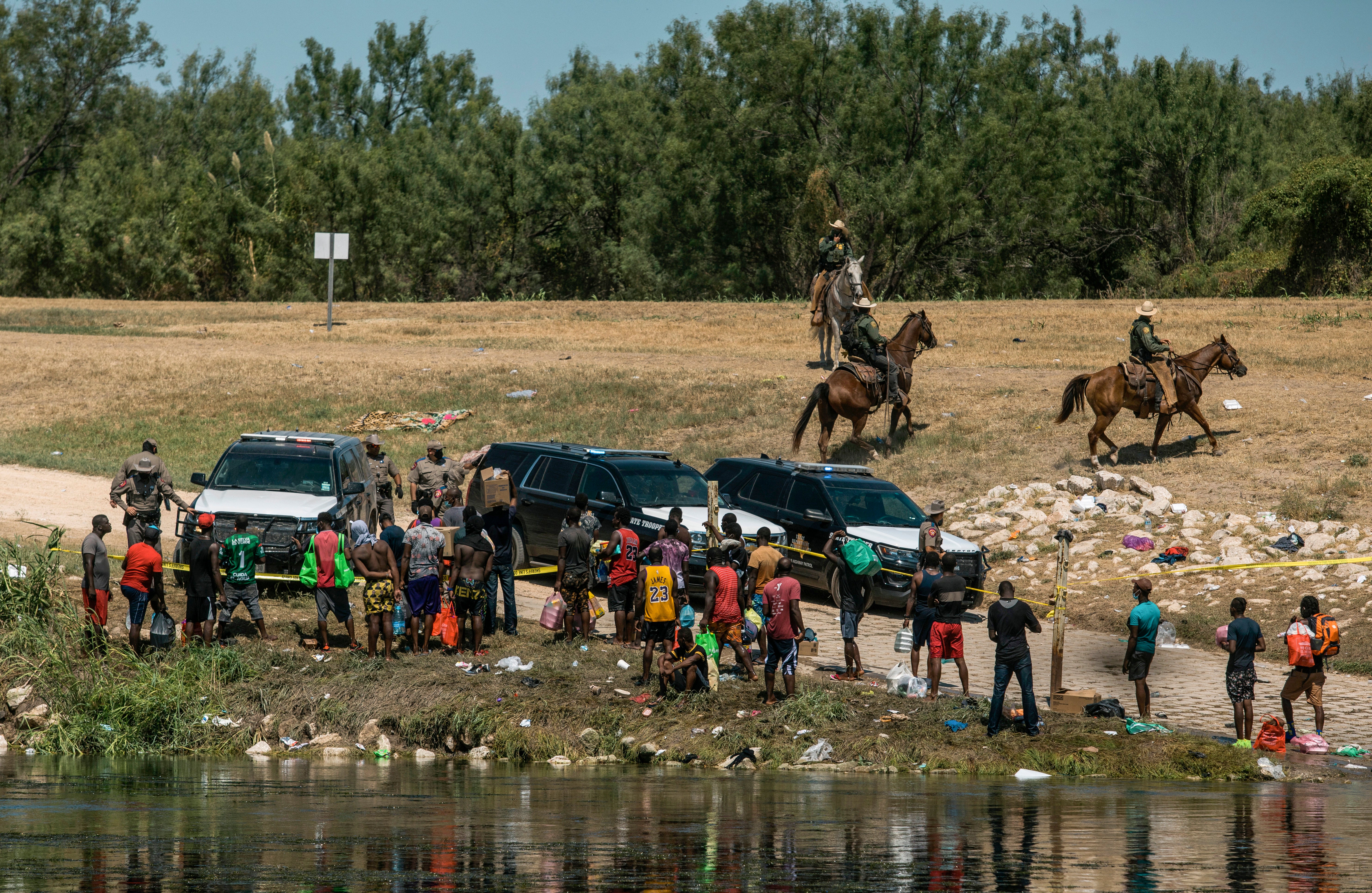 U.S. border patrol officers contain a group of migrants on the shore of the Rio Grande after they crossed from Mexico, into Del Rio, Texas, Sept. 19, 2021