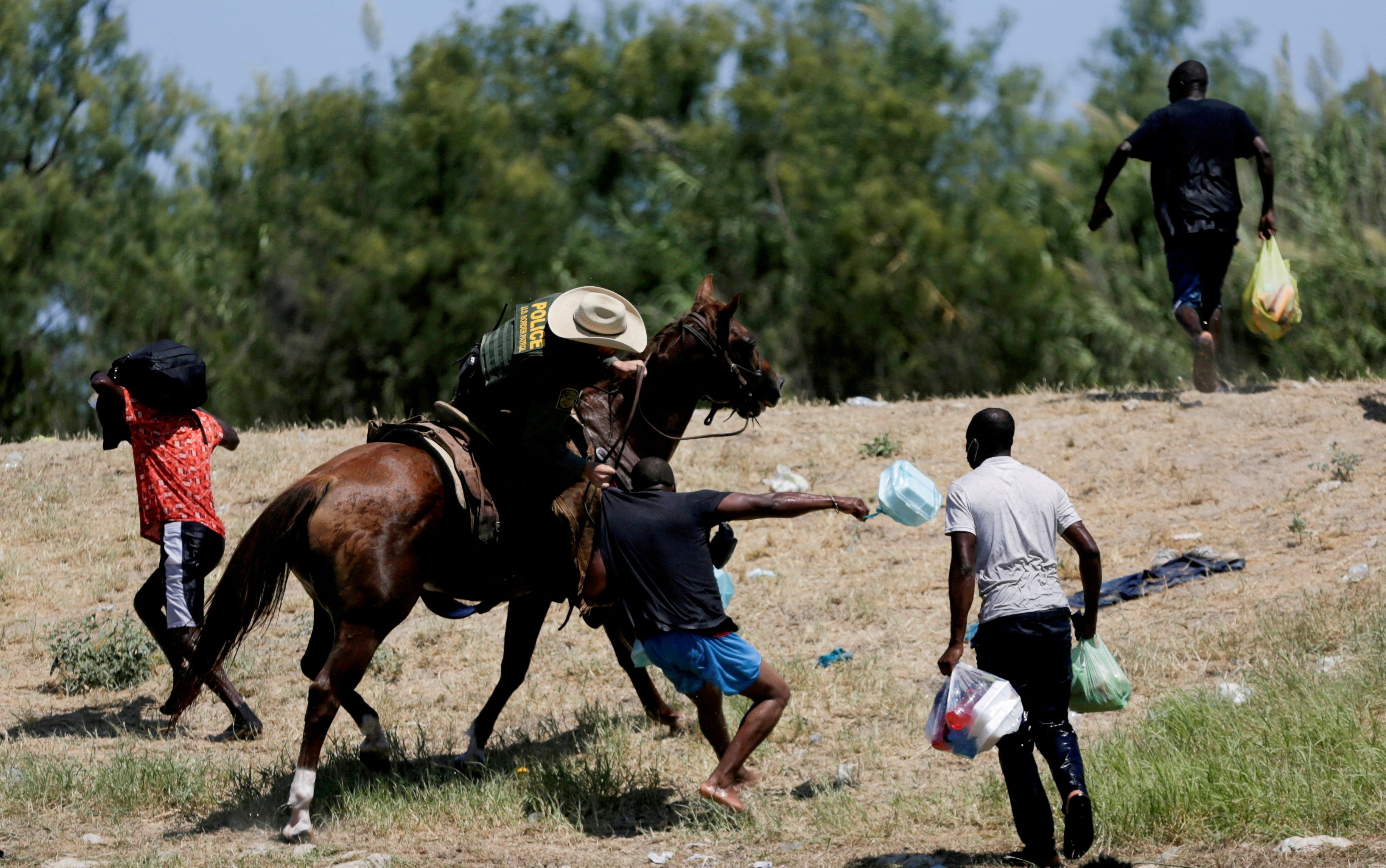 A U.S. border patrol officer grabs the shirt of a migrant trying to return to the United States along the Rio Grande river, after having crossed from the United States into Mexico to buy food, as seen from Ciudad Acuna, in Ciudad Acuna, Mexico September 19, 2021