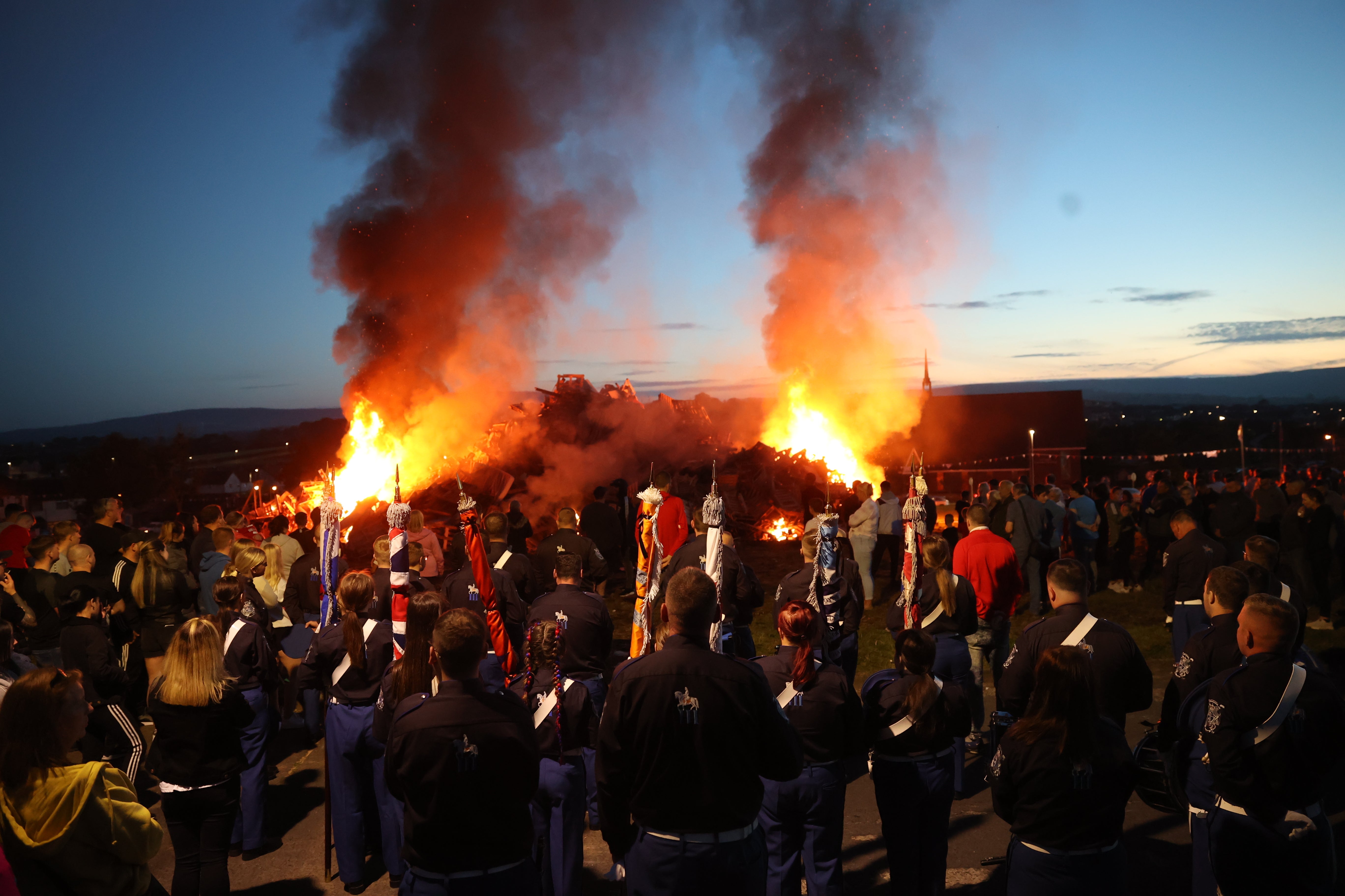 The dismantled bonfire is lit during a vigil where a man died after falling from the bonfire on the Antiville estate in Larne, Co Antrim. Picture date: Sunday July 10, 2022.