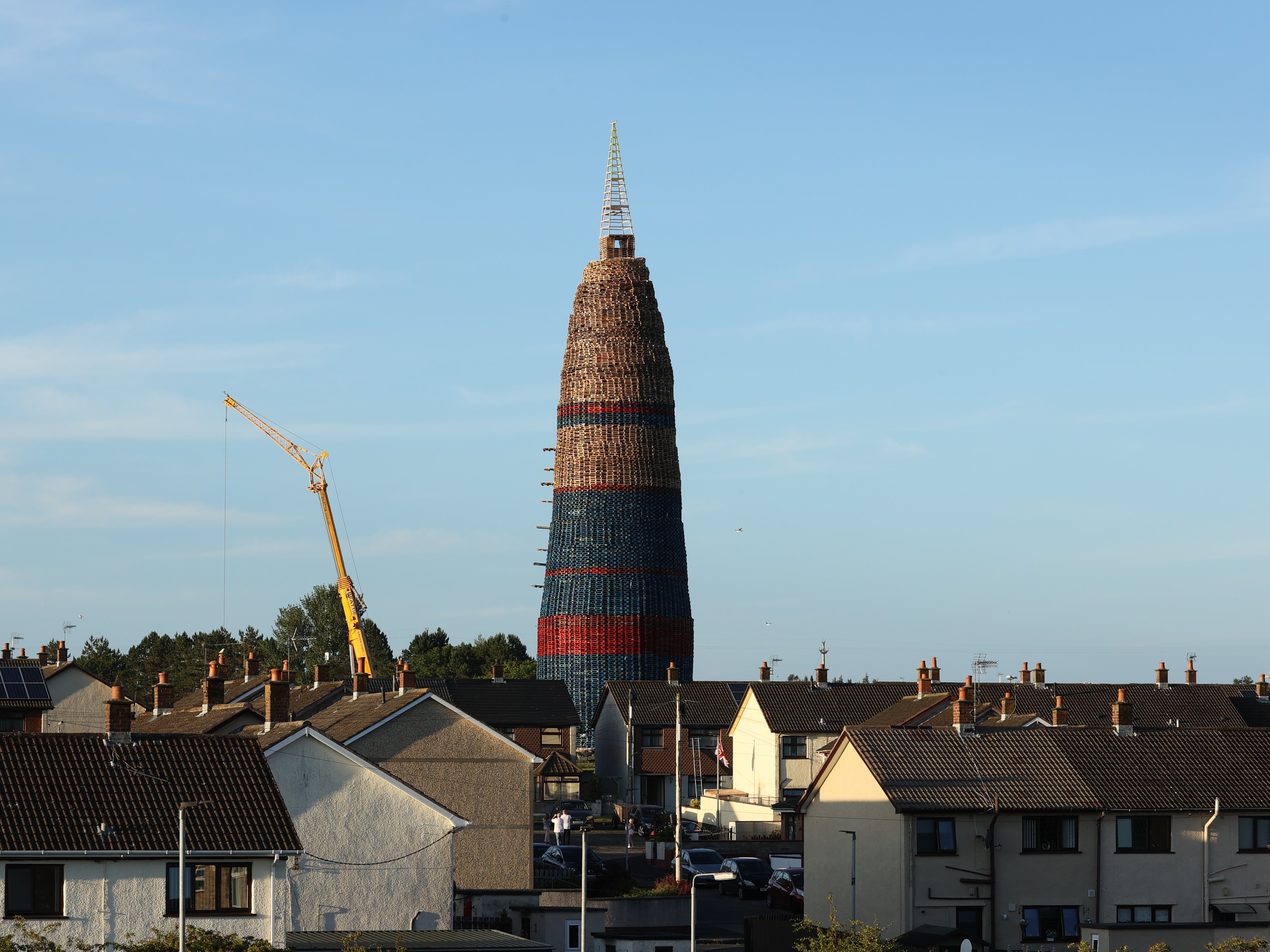 The Craigyhill Bonfire on the Craigyhill estate, Larne, Co Antrim, the builders are attempting to break a world record for the tallest bonfire, which currently stands at 198 feet. The builders say they will continue with their record bid in tribute to the man who died after falling from a bonfire on the nearby Antiville estate last night. Picture date: Sunday July 10, 2022.