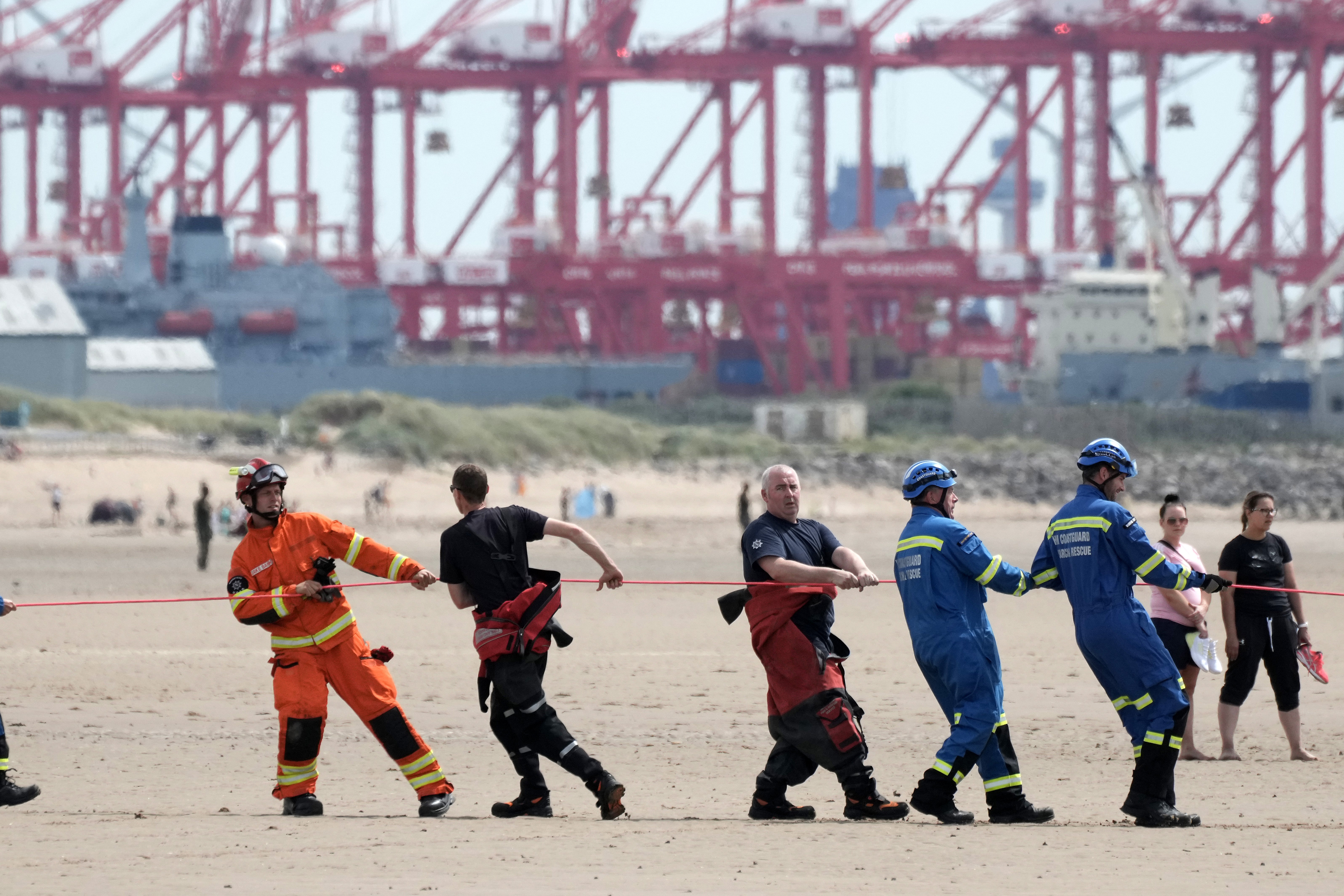 A heat haze shimmers over the Mersey estuary as the Coastguard rescue a man and a woman trapped in mud on Crosby Beach on Monday