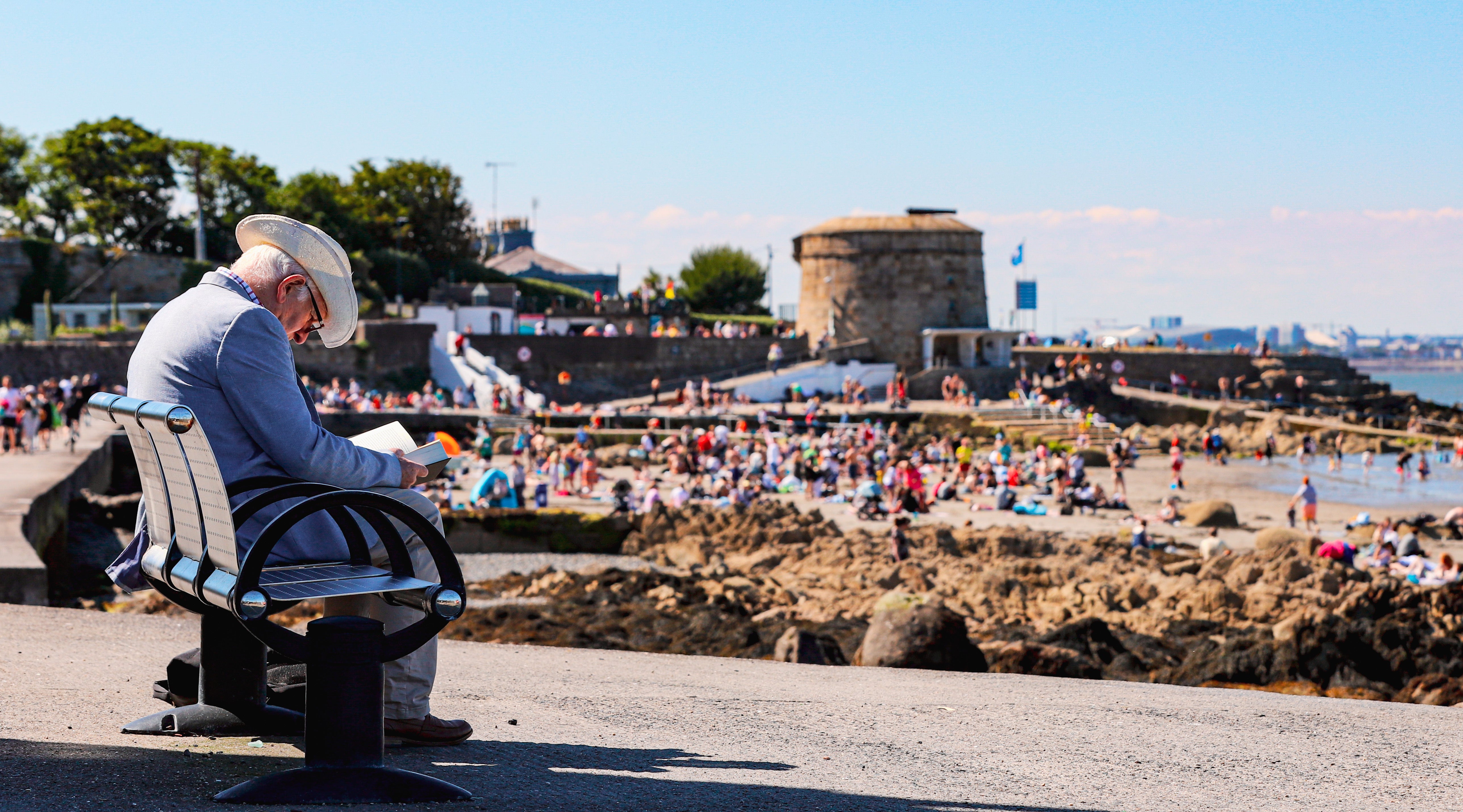 A man reads a book by himself during good weather at Seapoint Beach in South Dublin (Damien Storan/PA)