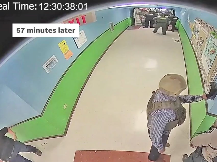 An officer is seen using a hand sanitizer dispenser roughly 57 minutes after a gunman entered Robb Elementary School in Uvalde, Texas, and killed 19 children and two teachers on 24 May, as law enforcement waited more than an hour to barge into the classroom and kill him.