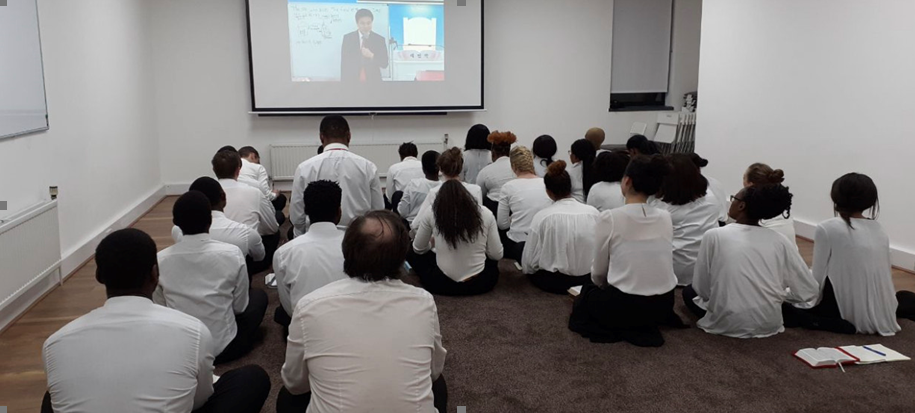 New Heaven New Earth members sit and watch a video stream from the leaders in South Korea