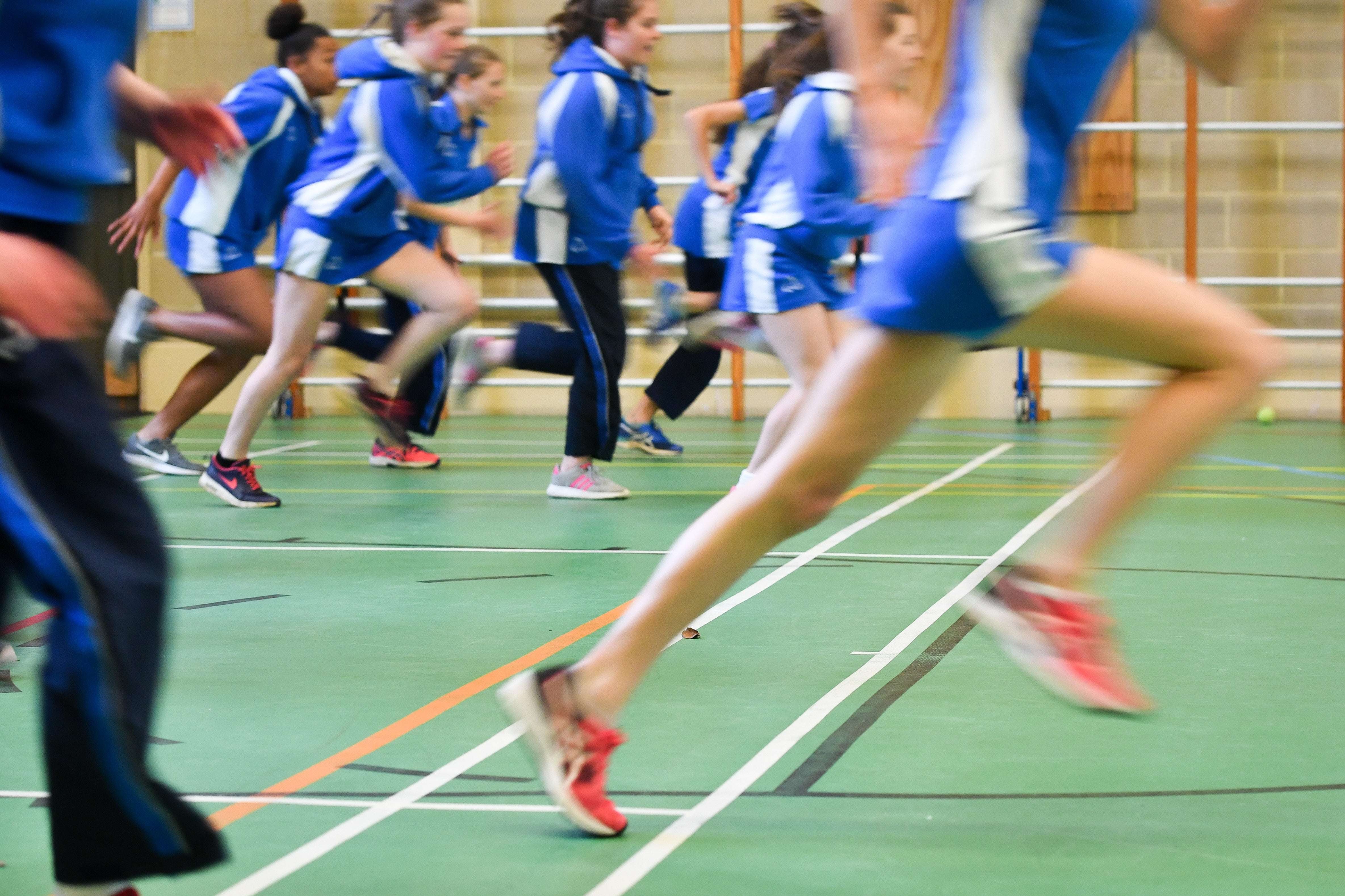 Pupils run during a PE lesson inside a sports hall (PA)