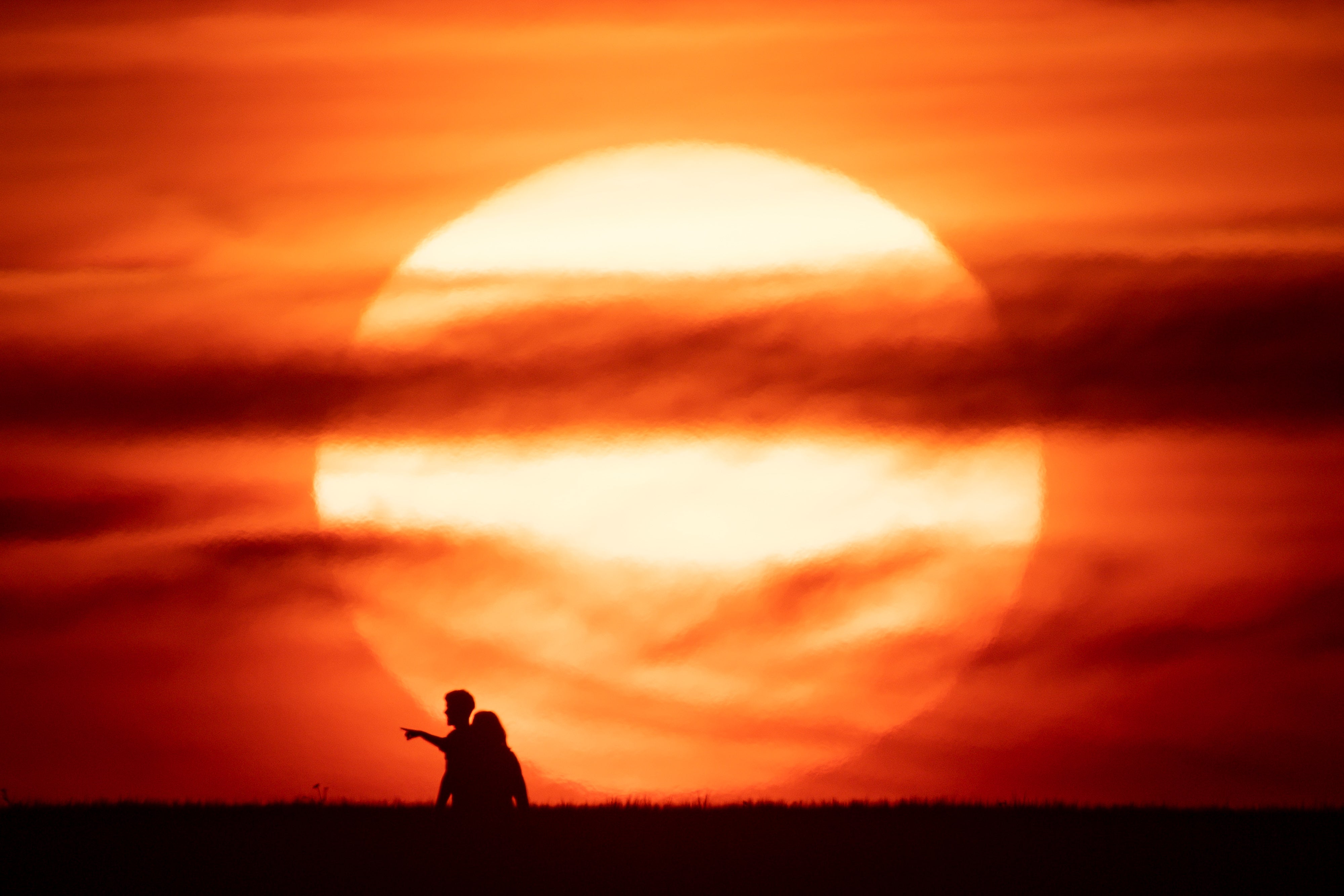 People in front of the sunset (Jacob King/PA)