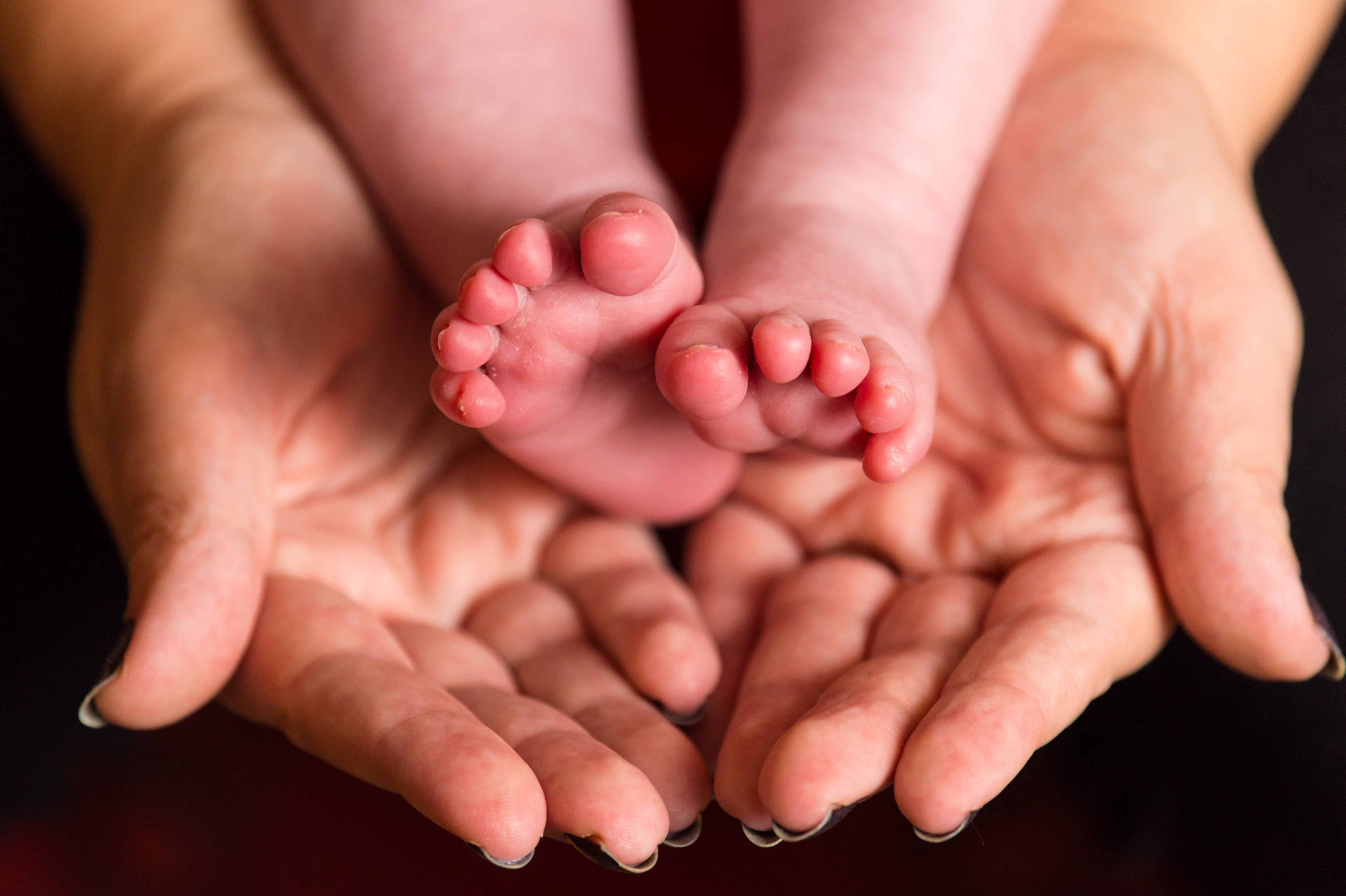 A mother holds the feet of a new baby (Dominic Lipinski/PA)