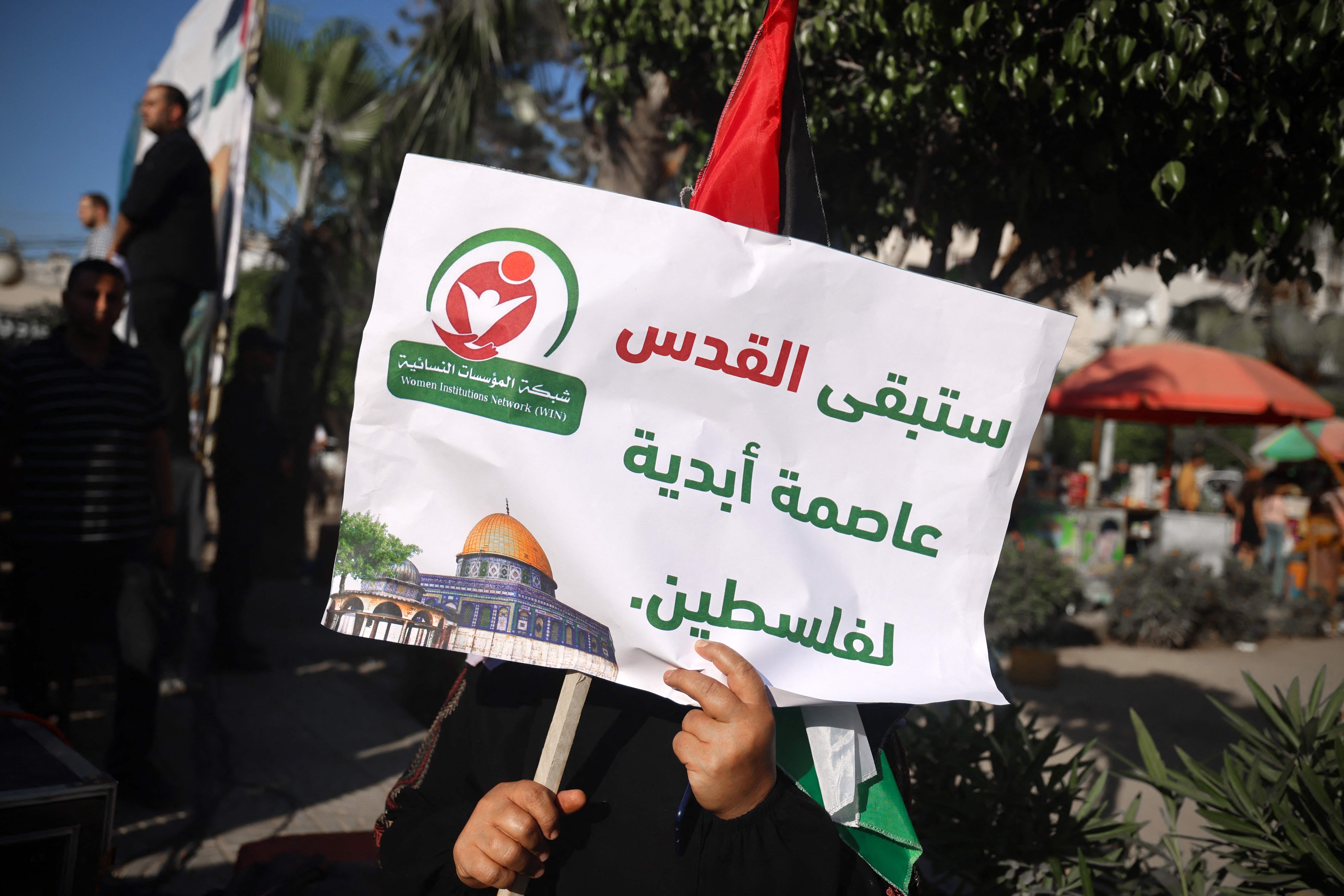 A Palestinian demonstrator carries a placard which reads ‘Jerusalem is the eternal capital of Palestine' during a gathering to protest the visit of US president Joe Biden, in Gaza City on 14 July 2022