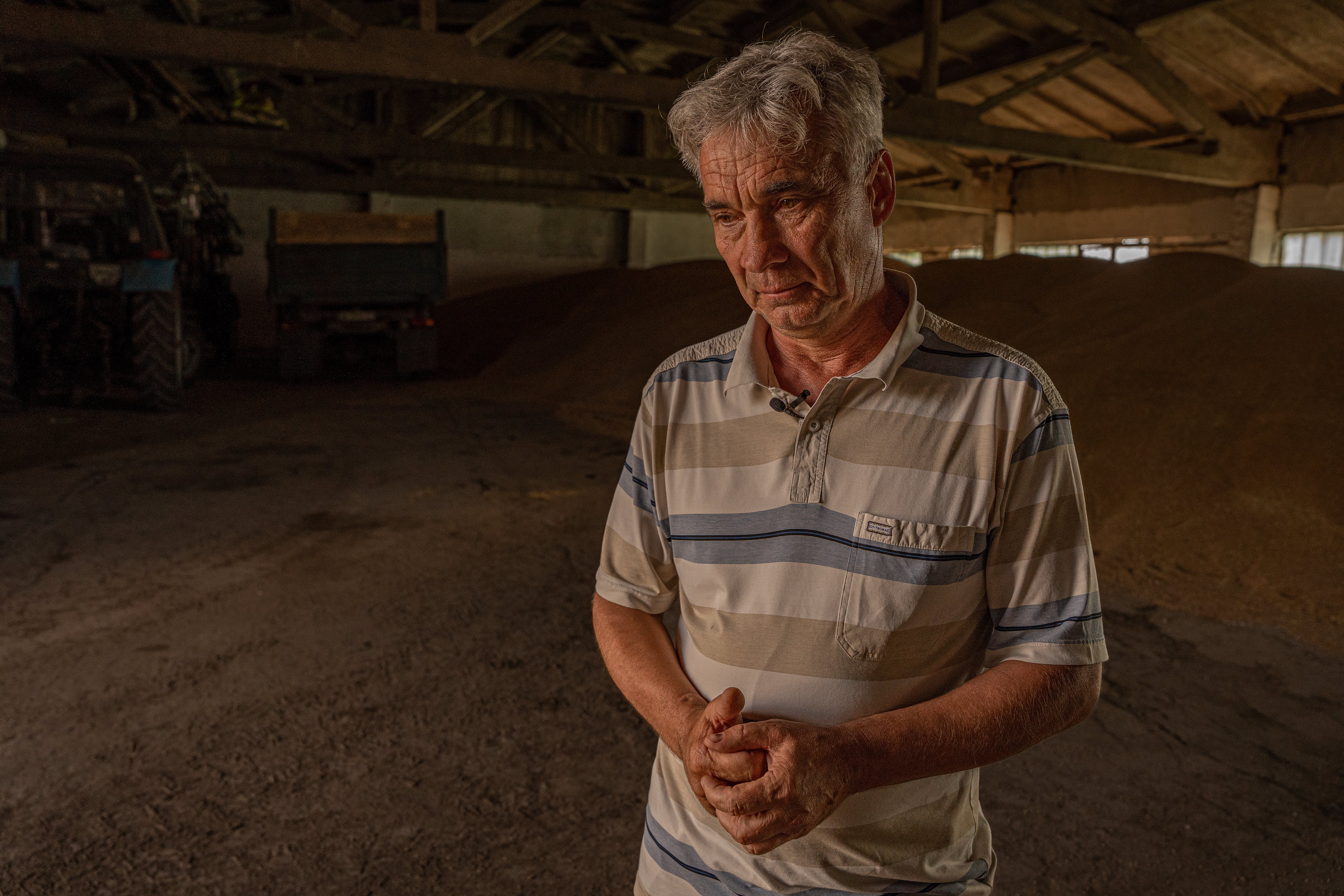 Vadym Martov, a farmer in Donbas, stands in front of last year’s harvest that he can’t ship. He can only sell his new harvest for a third of what it costs to produce