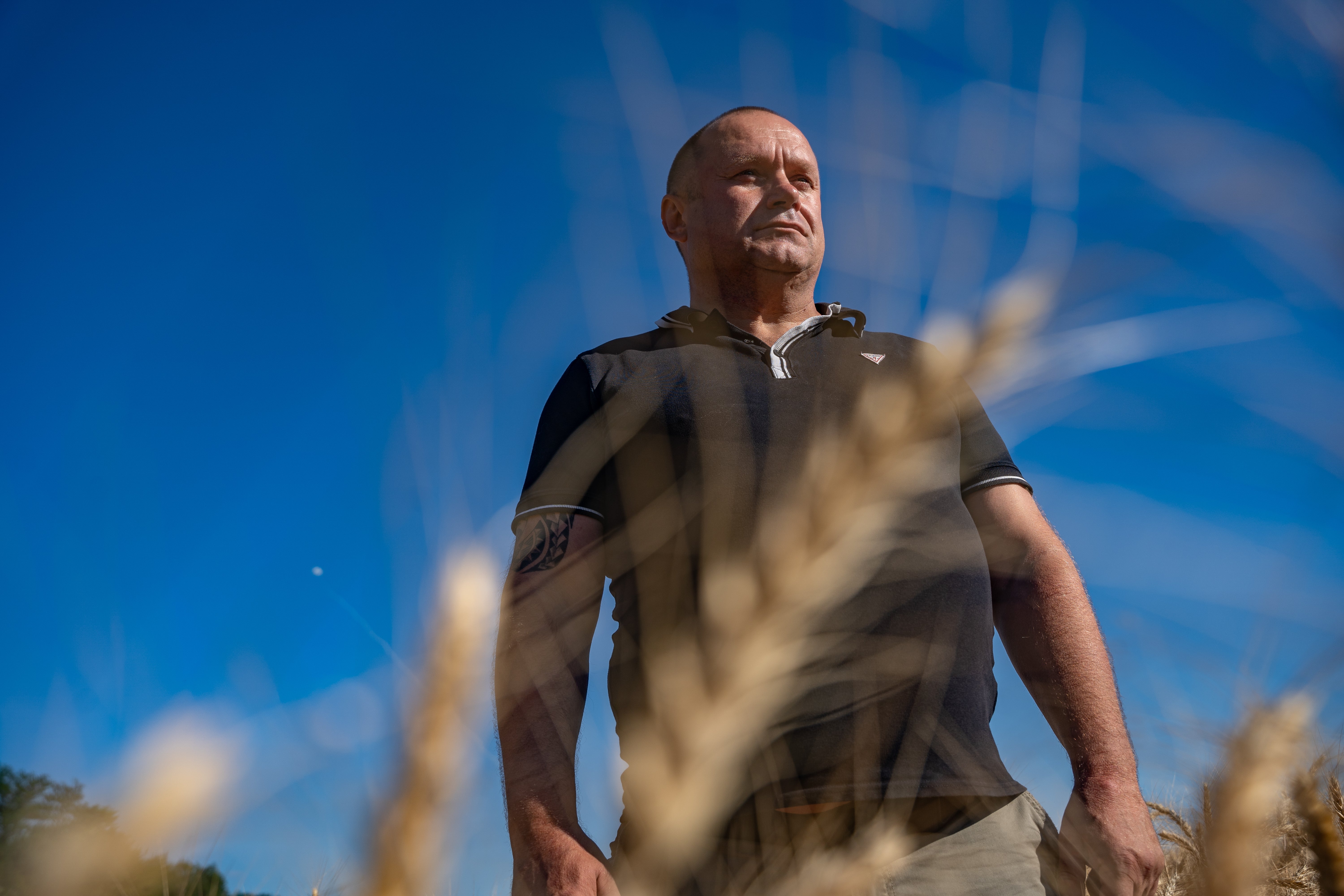 Oleksander Chebanov, 49, a farmer in Dnipro stands in his field with the white smoke of a missile being shot down behind him