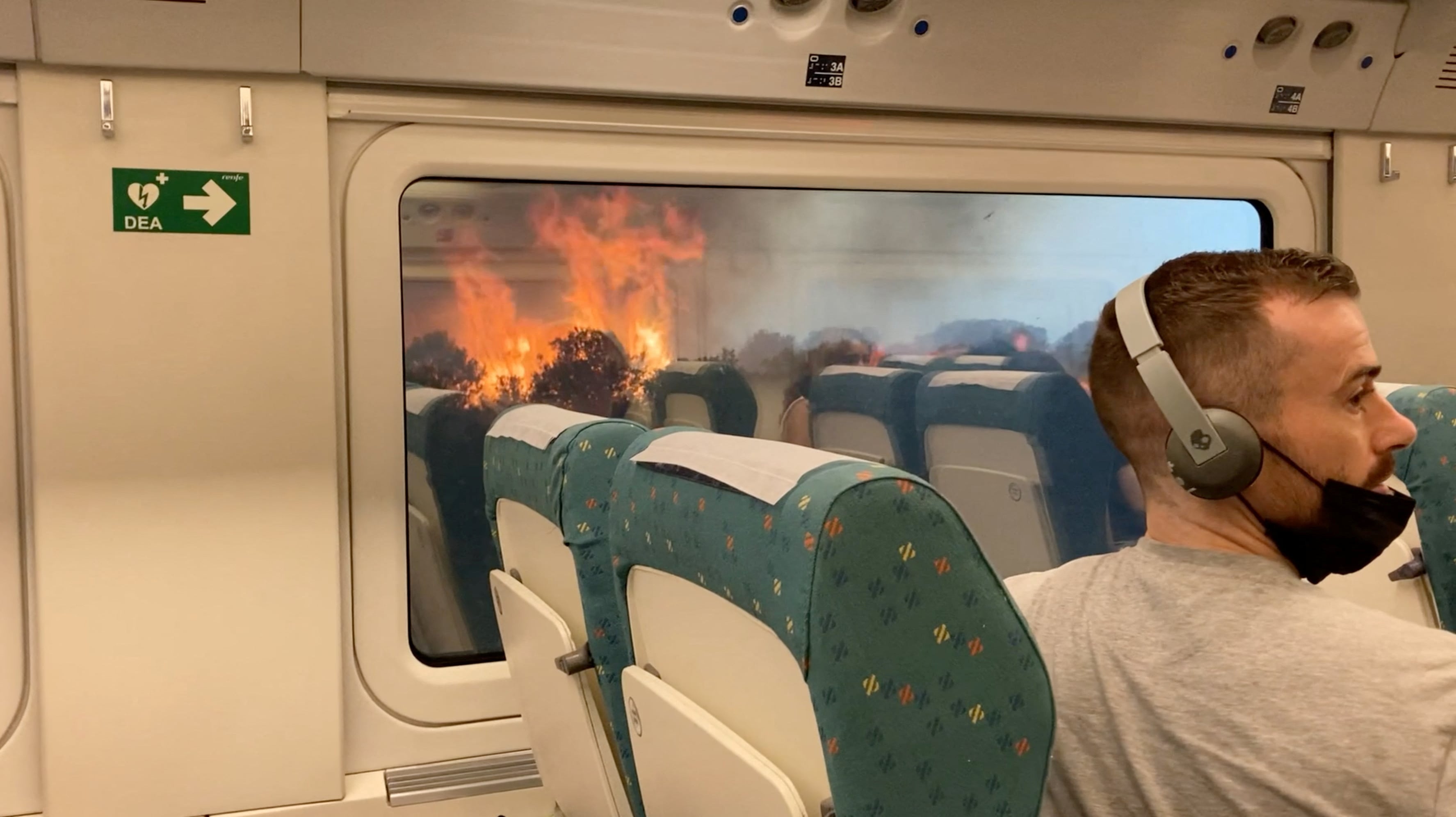 Passengers look at the wildfire from train, near Zamora, Spain