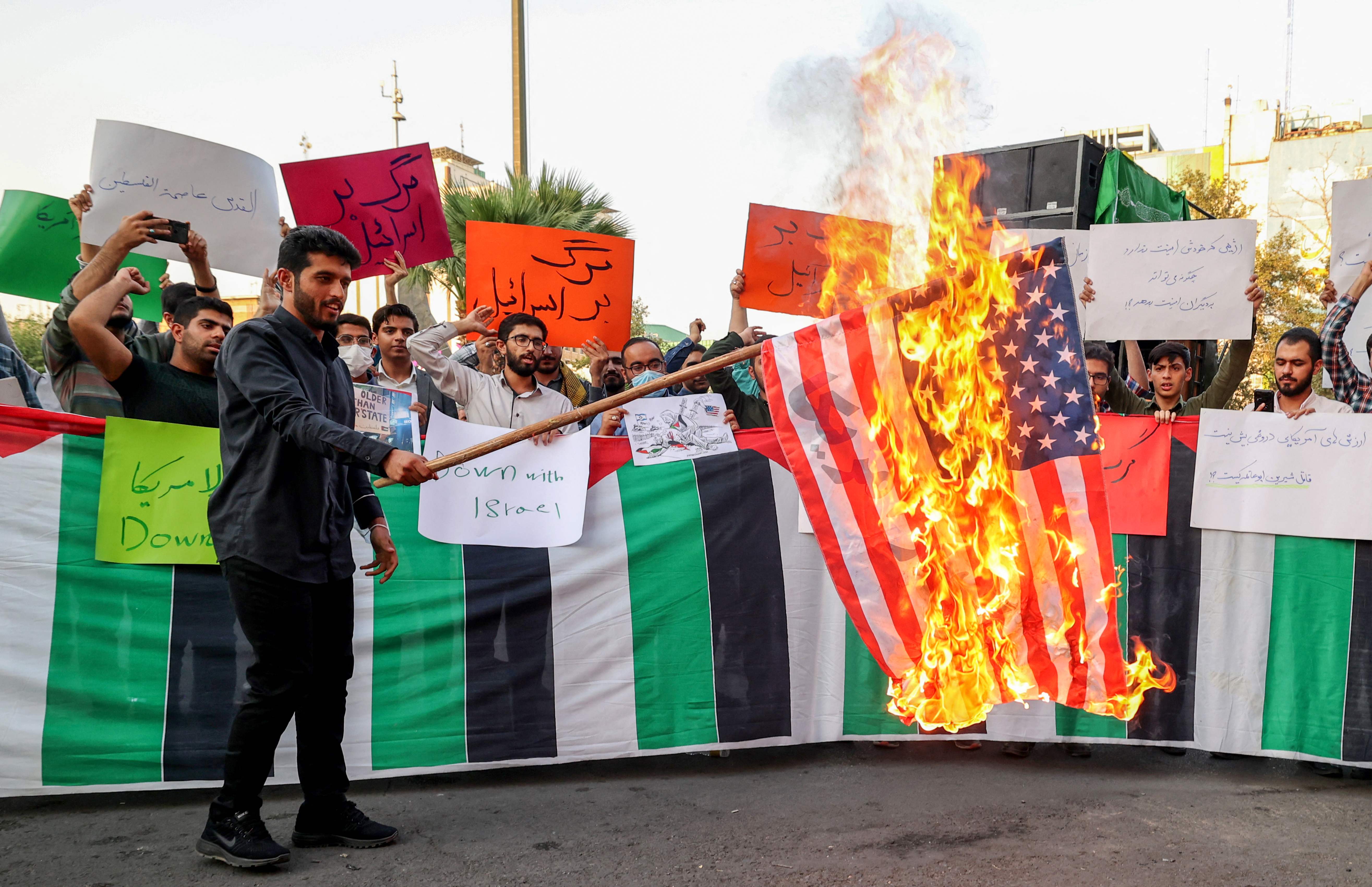 An Iranian student from the Islamic Basiji volunteer militia burns a US flag in Iran’s capital Tehran during a protest against the US president’s visits to Israel and Saudi Arabia