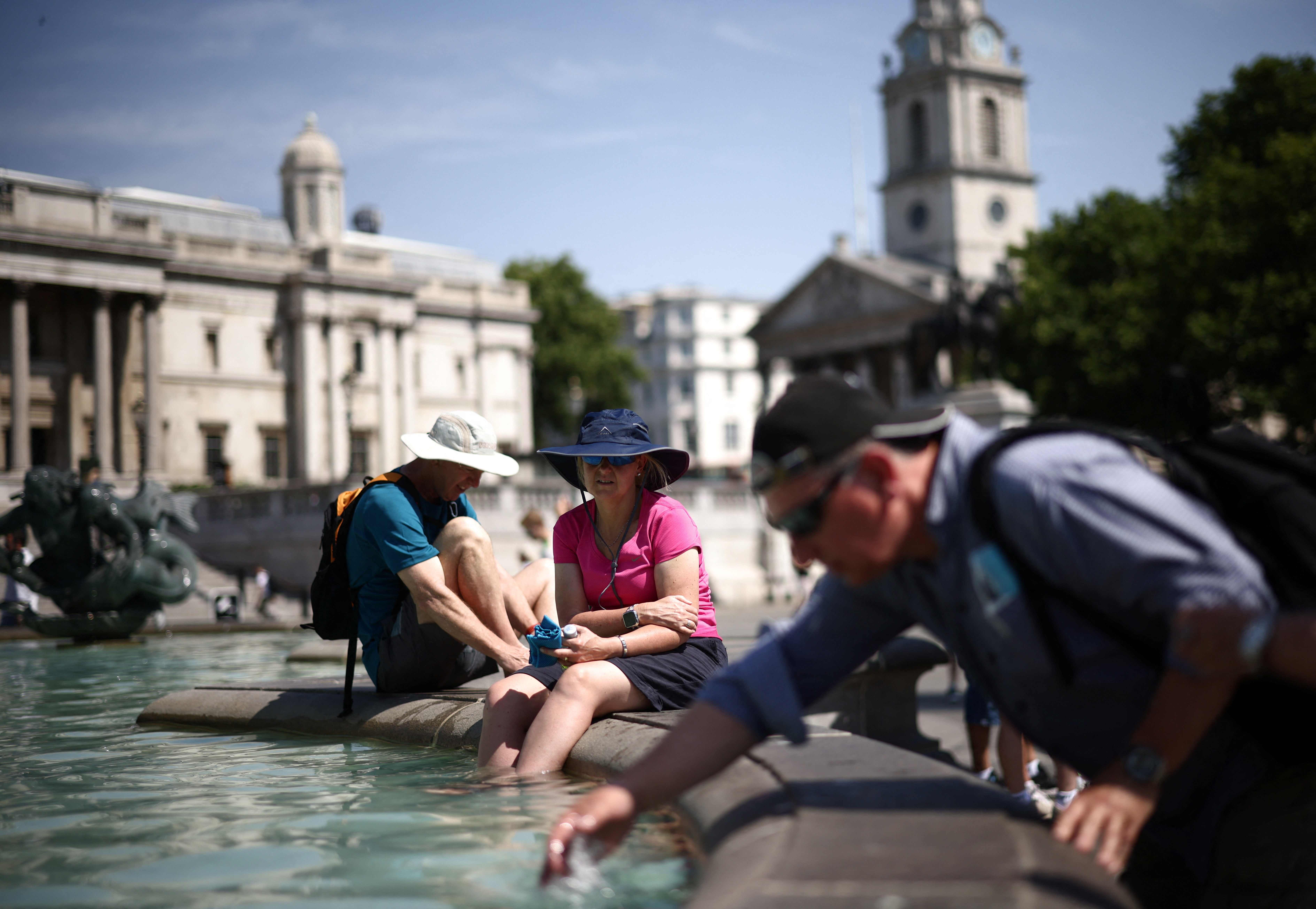 People cool off in a water fountain during a heatwave, at Trafalgar Square in London.