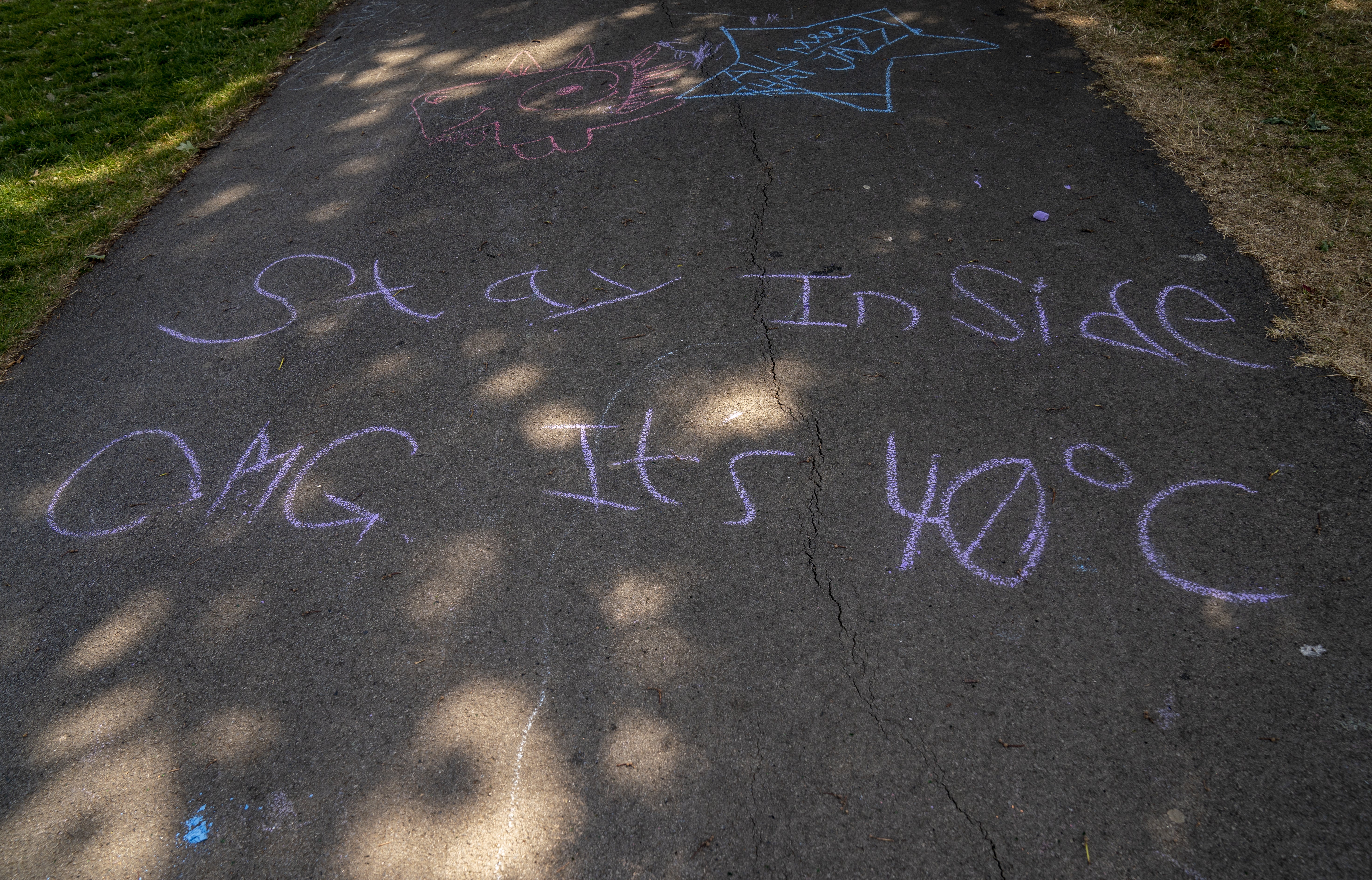 Writing on the ground in Sandall Park, Doncaster that reads “stay inside OMG it’s 40C” (Danny Lawson/PA)