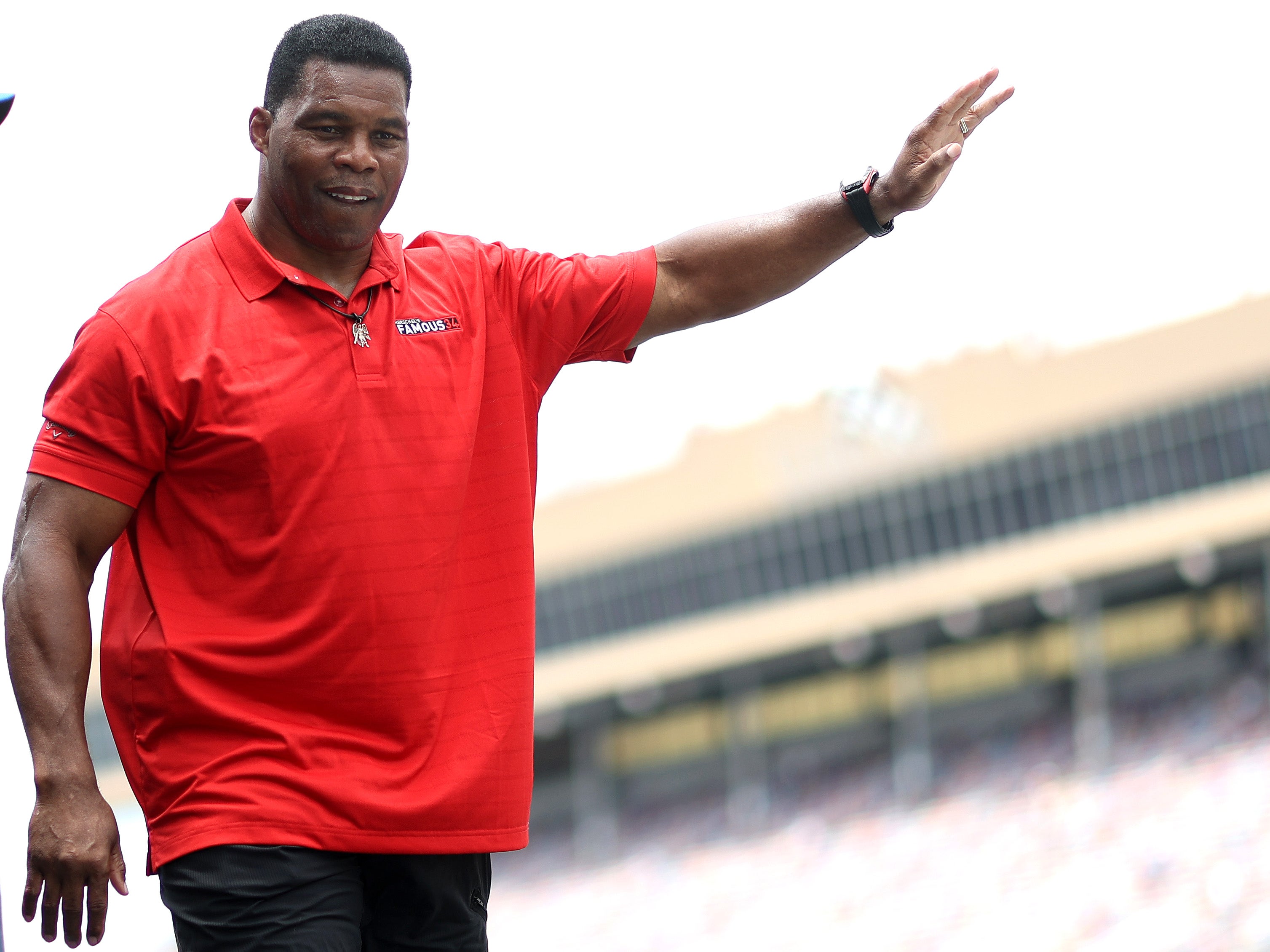 Republican candidate for US Senate Herschel Walker waves to fans as he walks onstage during pre-race ceremonies prior to the NASCAR Cup Series Quaker State 400 at Atlanta Motor Speedway on July 10, 2022 in Hampton, Georgia