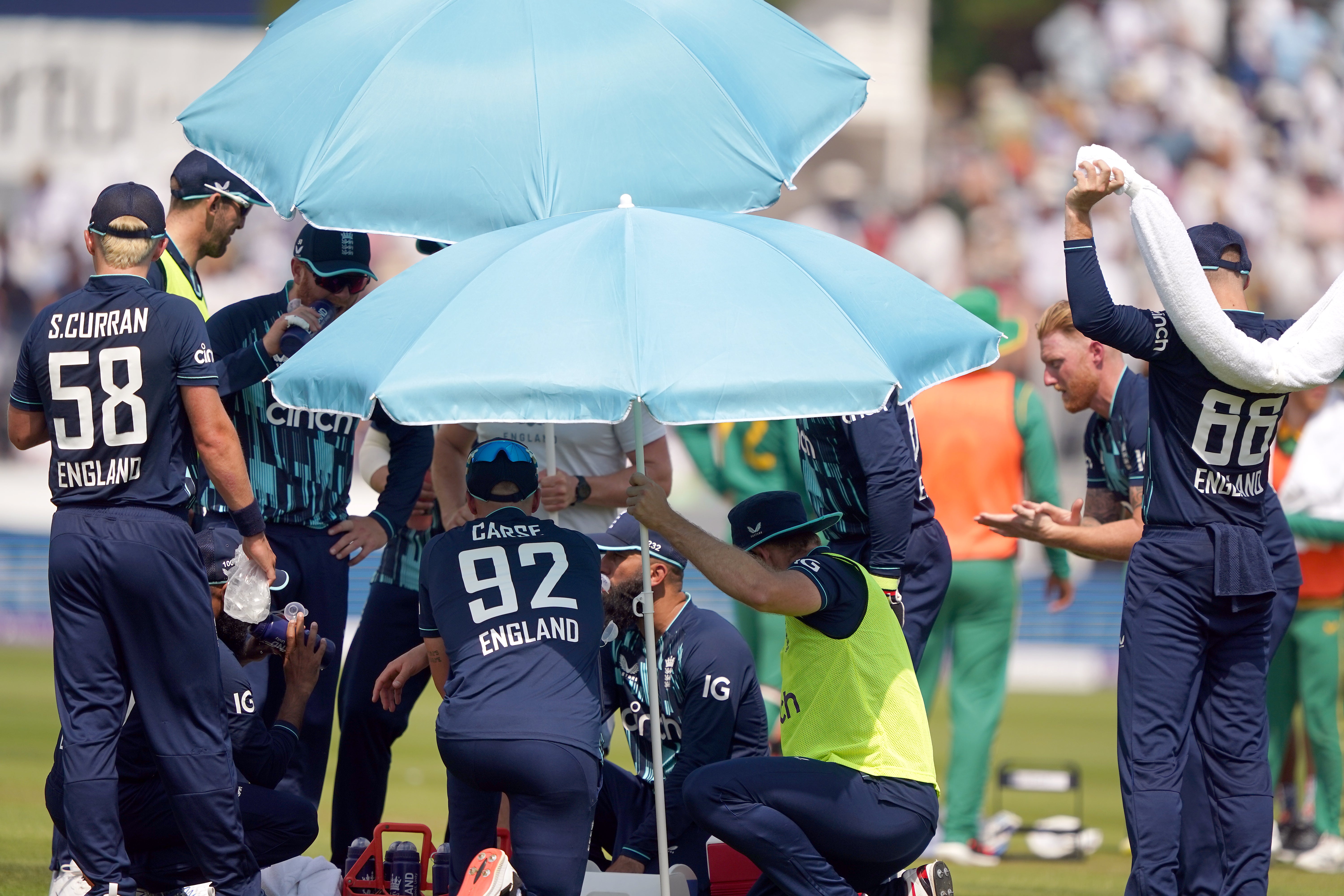 England players shelter under umbrellas as they take a drinks break and use ice to cool down (Owen Humphreys/PA)