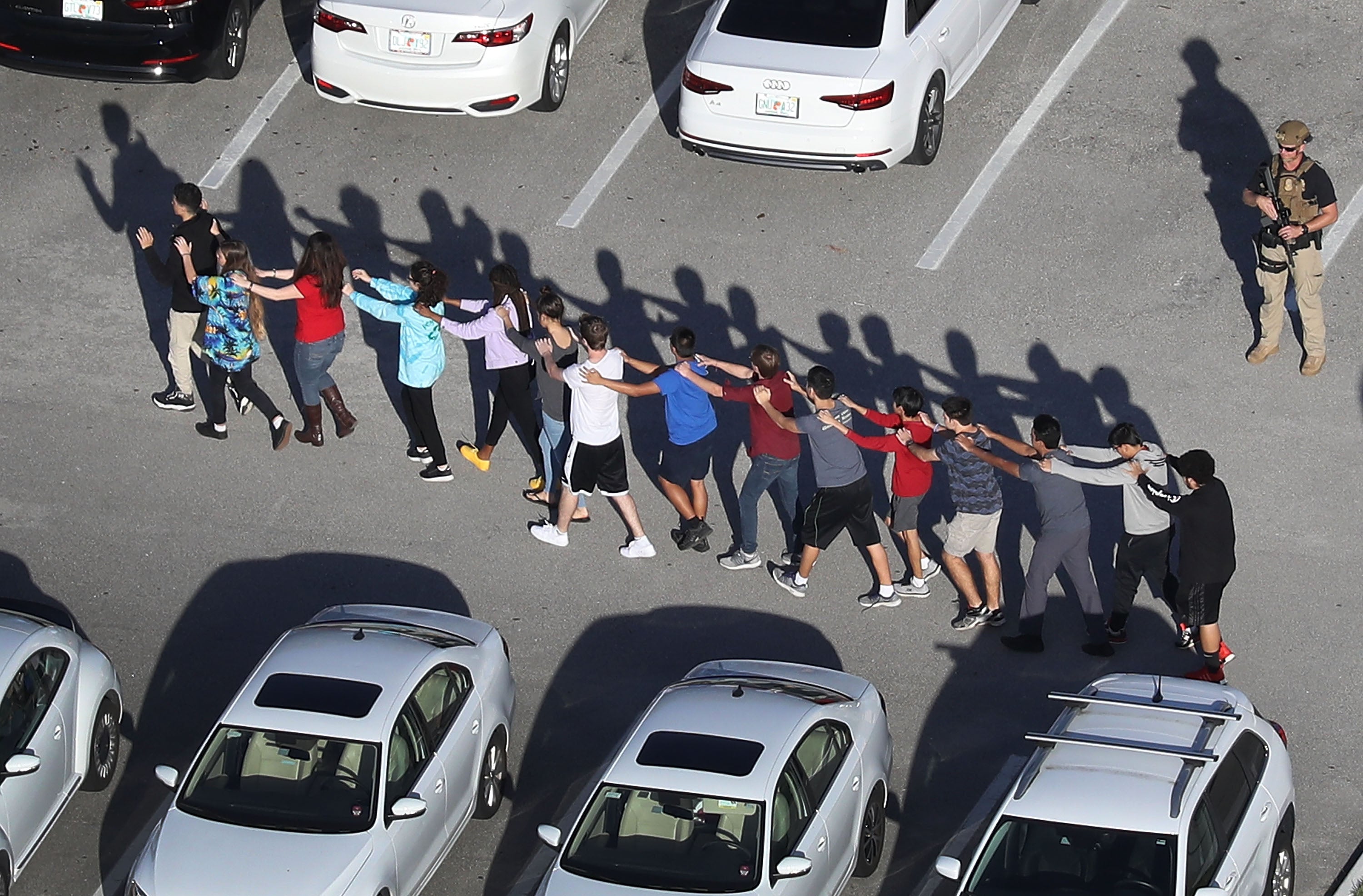 People are brought out of the Marjory Stoneman Douglas High School after the February 14, 2018, Parkland shooting.