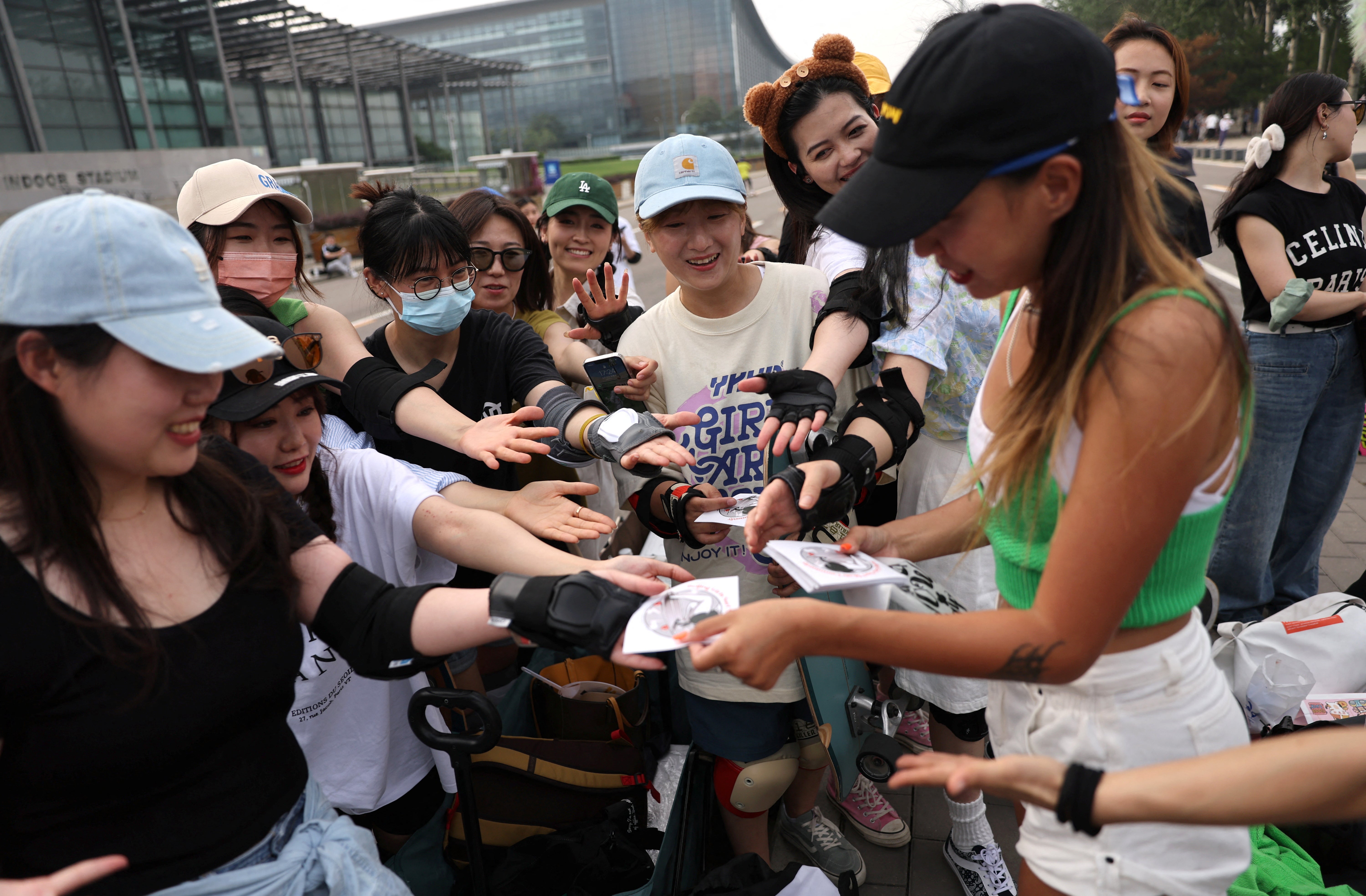 The founder of Beijing Girls Surfskating Community, distributes stickers with the community's logo to the members, during a free weekly training session in Beijing