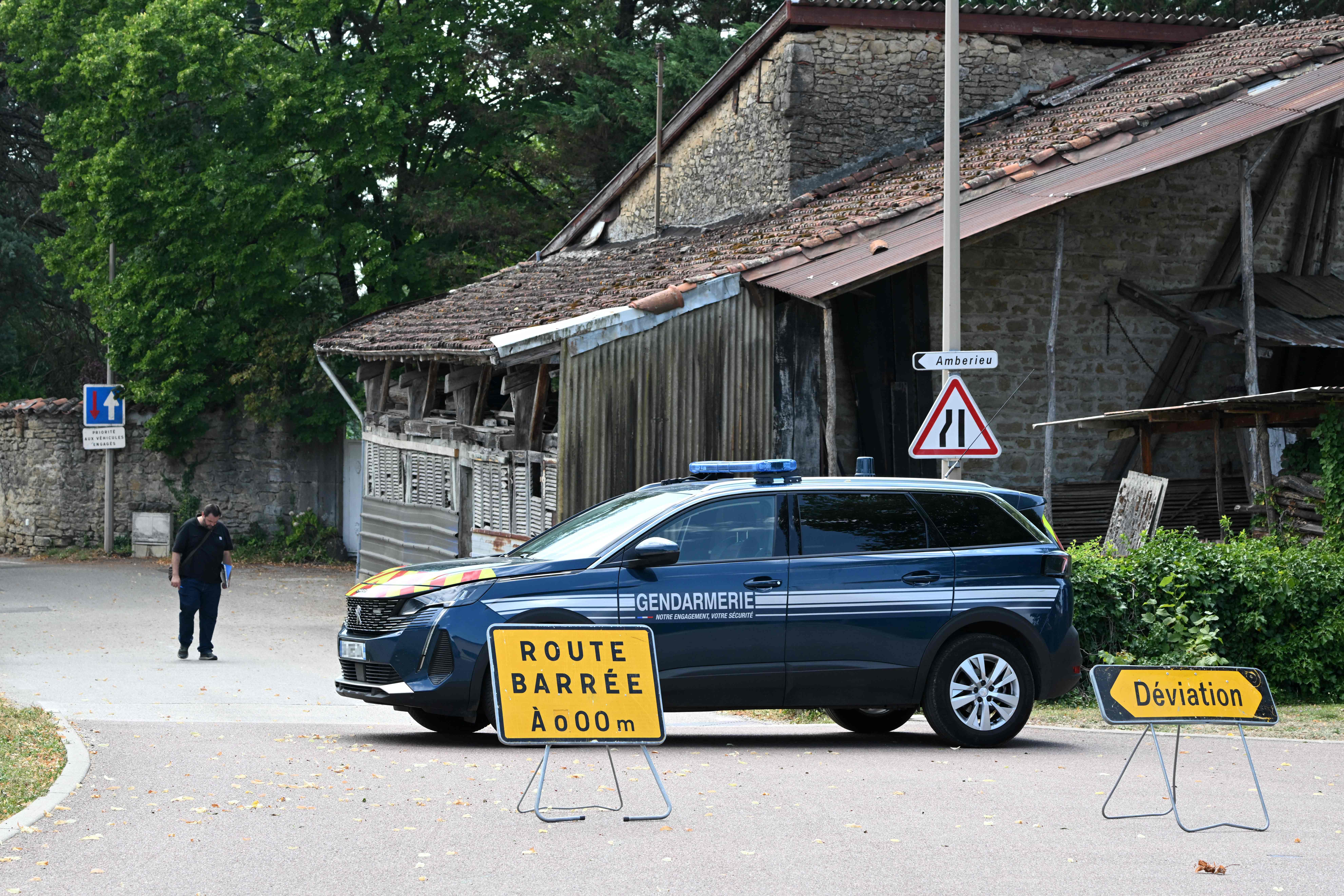 French gendarmerie car blocks the road leading to the house in which a man suspected of having shot five people barricaded himself