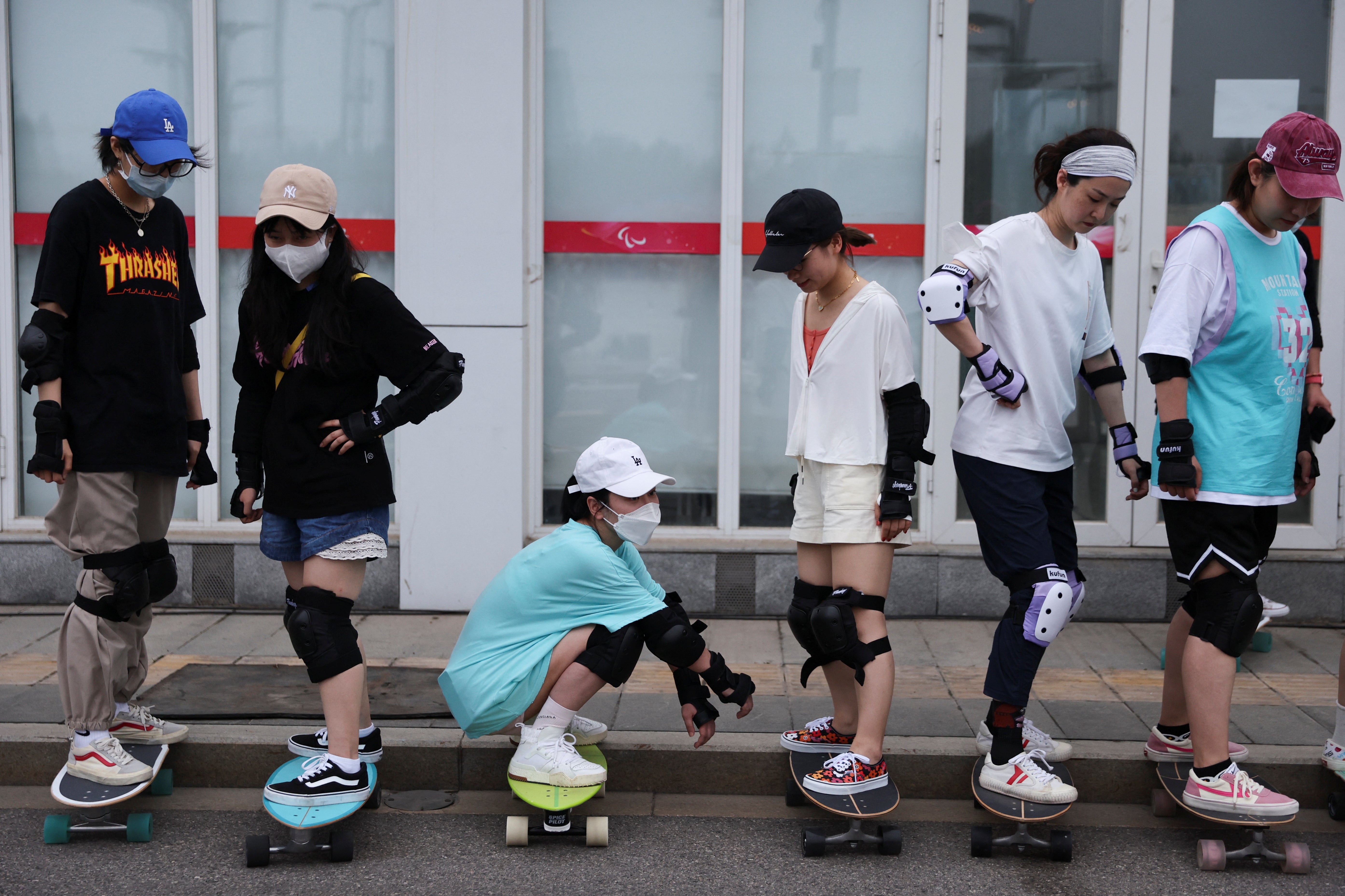 Members of Beijing Girls Surfskating Community stand on skateboards as they attend a training session for beginners
