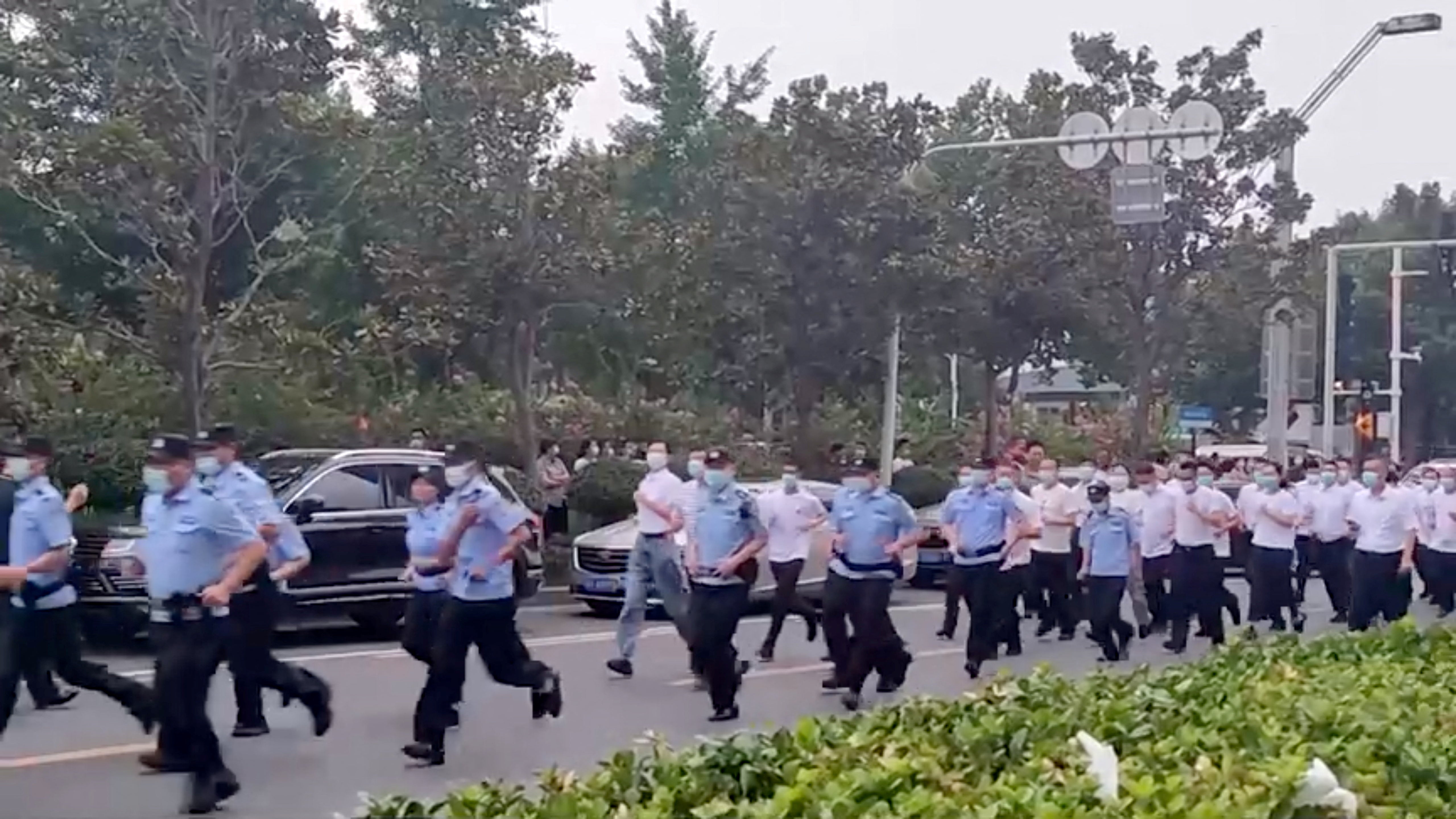 Uniformed and plain-clothed security personnel run to approach demonstrators in Zhengzhou