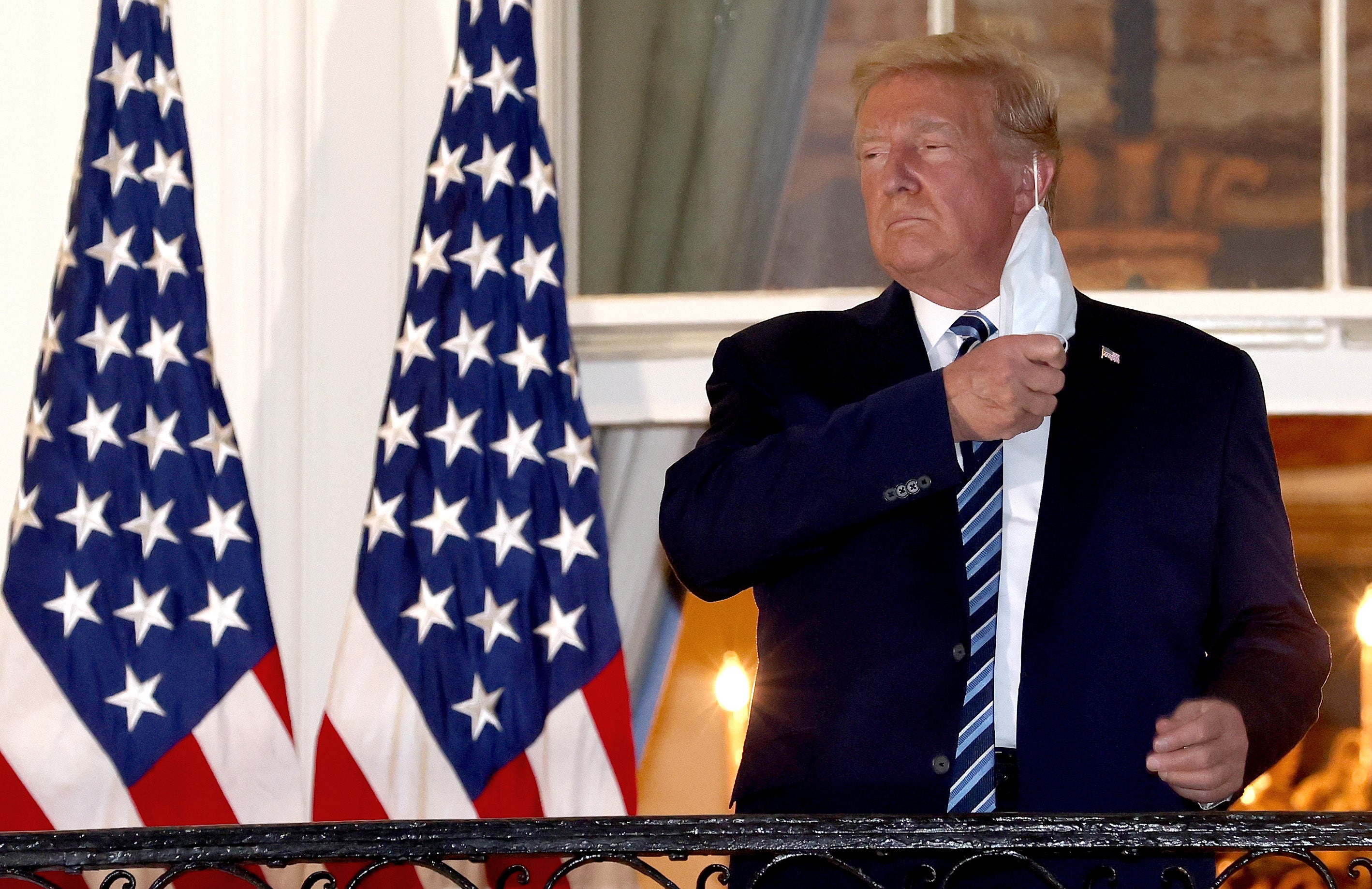 U.S. President Donald Trump removes his mask upon return to the White House from Walter Reed National Military Medical Center on October 05, 2020 in Washington, DC