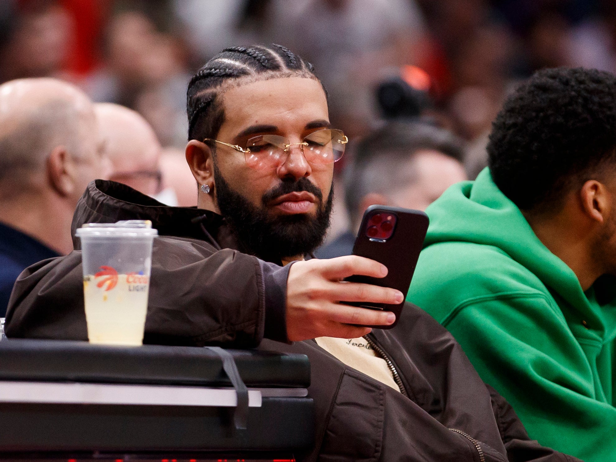 Rapper Drake texts while watching Game Six of the Eastern Conference First Round between the Toronto Raptors and the Philadelphia 76ers at Scotiabank Arena on April 28, 2022 in Toronto, Canada. NOTE TO USER: User expressly acknowledges and agrees that, by downloading and or using this Photograph, user is consenting to the terms and conditions of the Getty Images License Agreement. (Photo by Cole Burston/Getty Images)