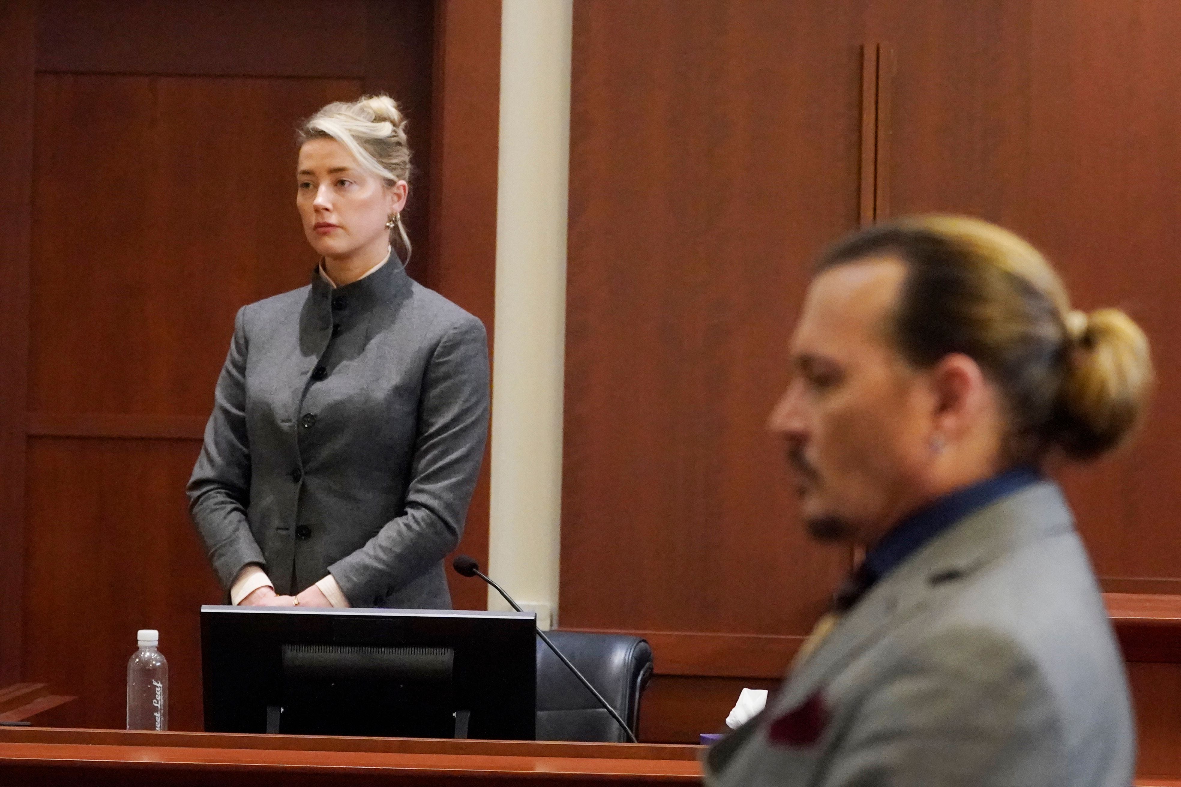 Los actores estadounidenses Amber Heard (izquierda) y Johnny Depp observan cómo el jurado abandona la sala del tribunal al final del día en el juzgado de circuito del condado de Fairfax en Fairfax, Virginia, el 16 de mayo de 2022.