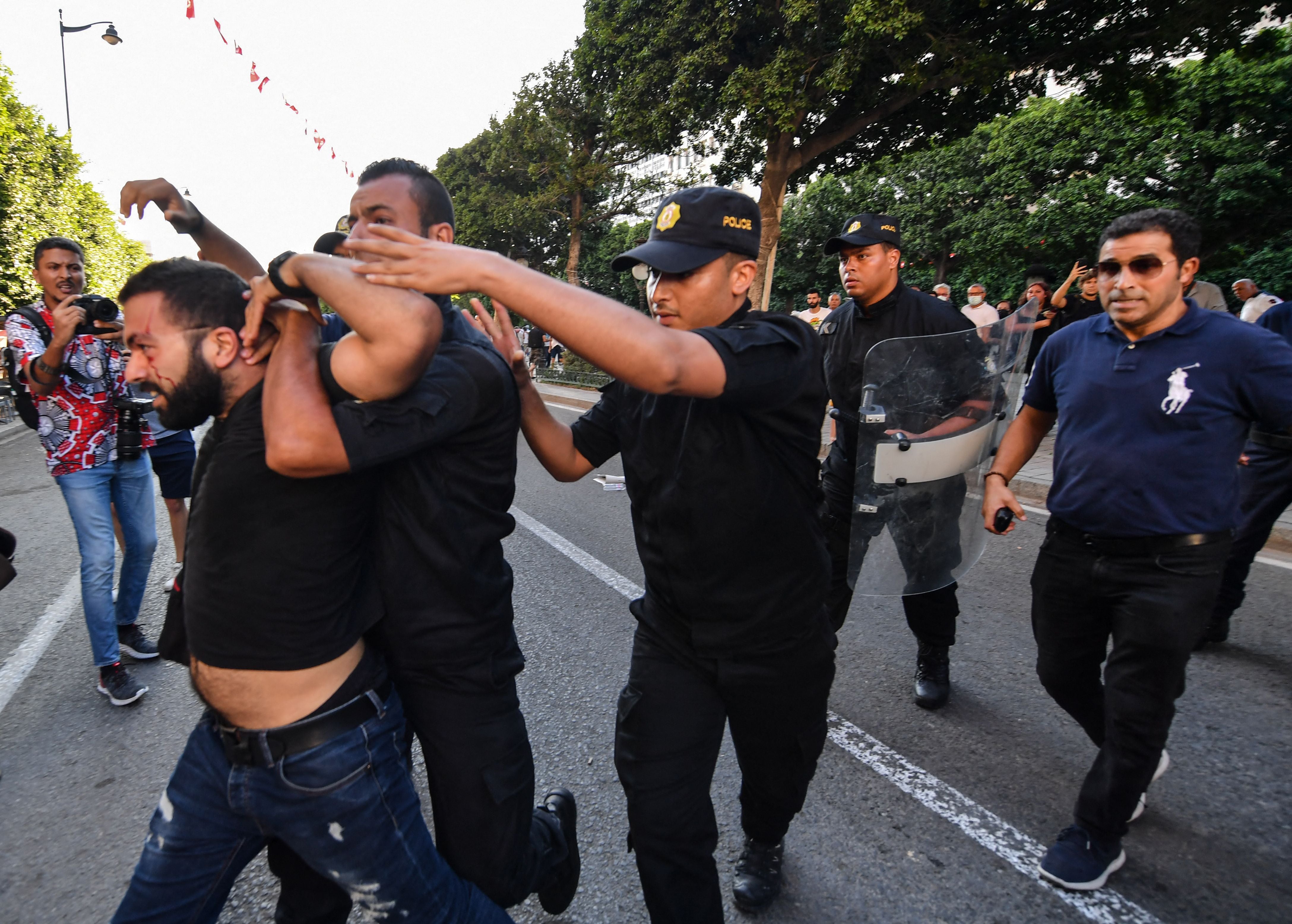 Tunisian policemen arrest a protester on July 22 during a demonstration in the capital, Tunis