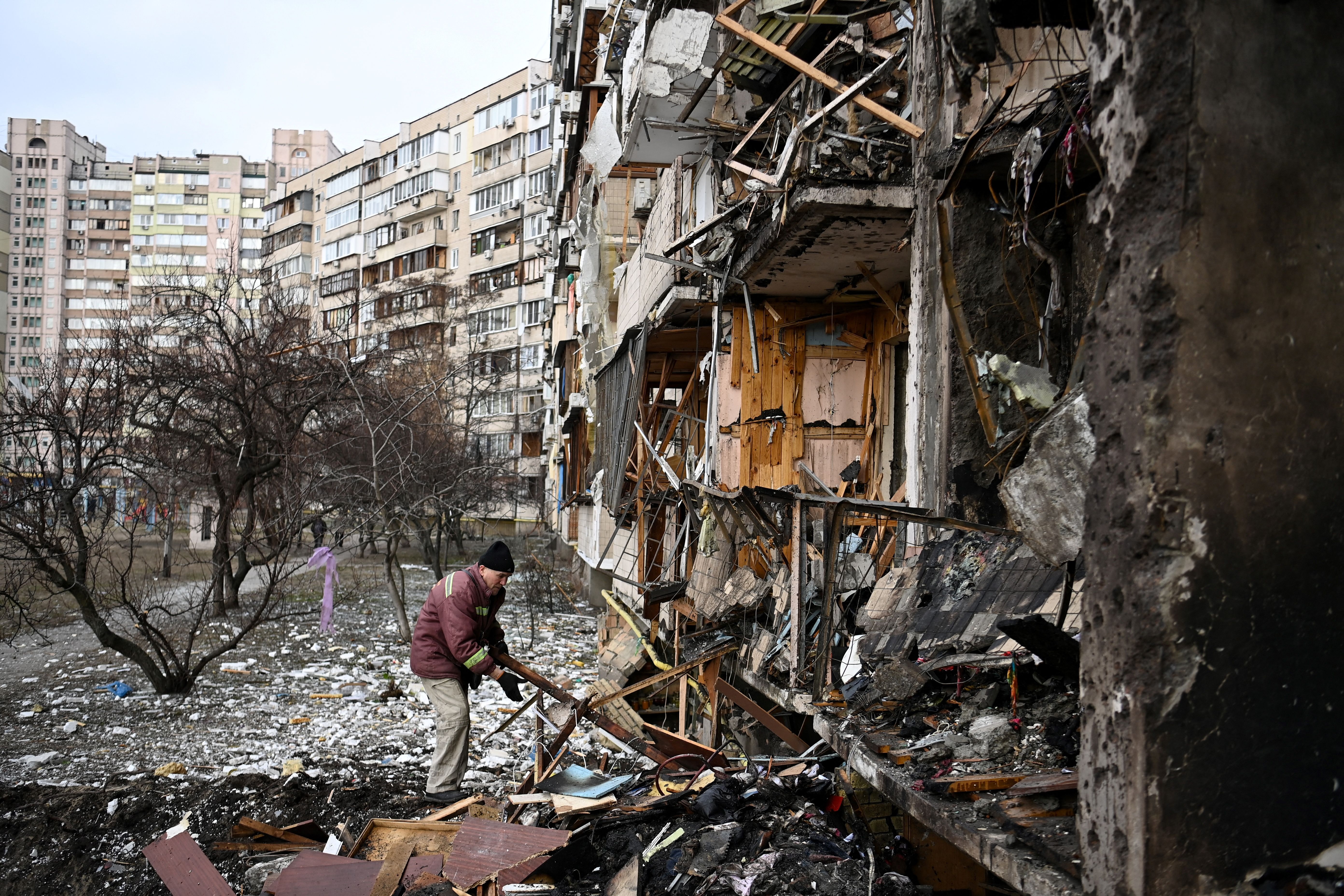 A man clears debris outside a residential building in a suburb of Kyiv