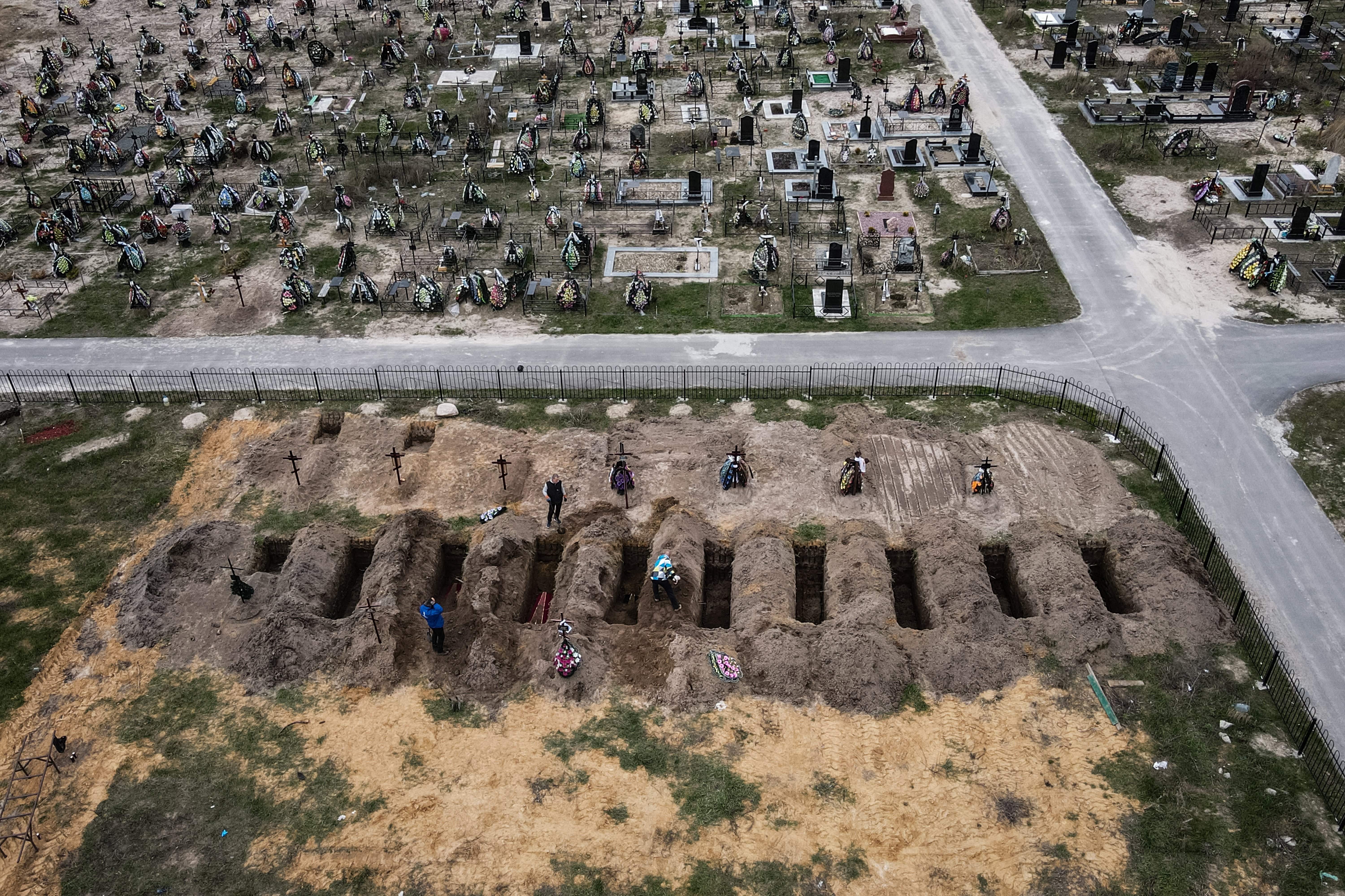 An aerial picture shows coffins being buried during a funeral ceremony at a cemetery in Bucha